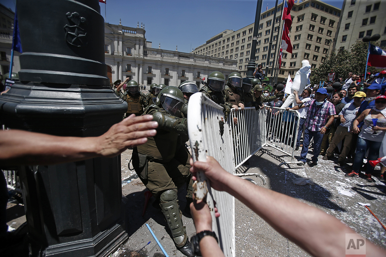  Public workers try to break past a police barrier to reach La Moneda presidential palace in Santiago, Chile, Thursday, Nov. 17, 2016. Workers upset with their salary increase, 3.2 percent approved Wednesday by Congress, want a 4 percent increase, af