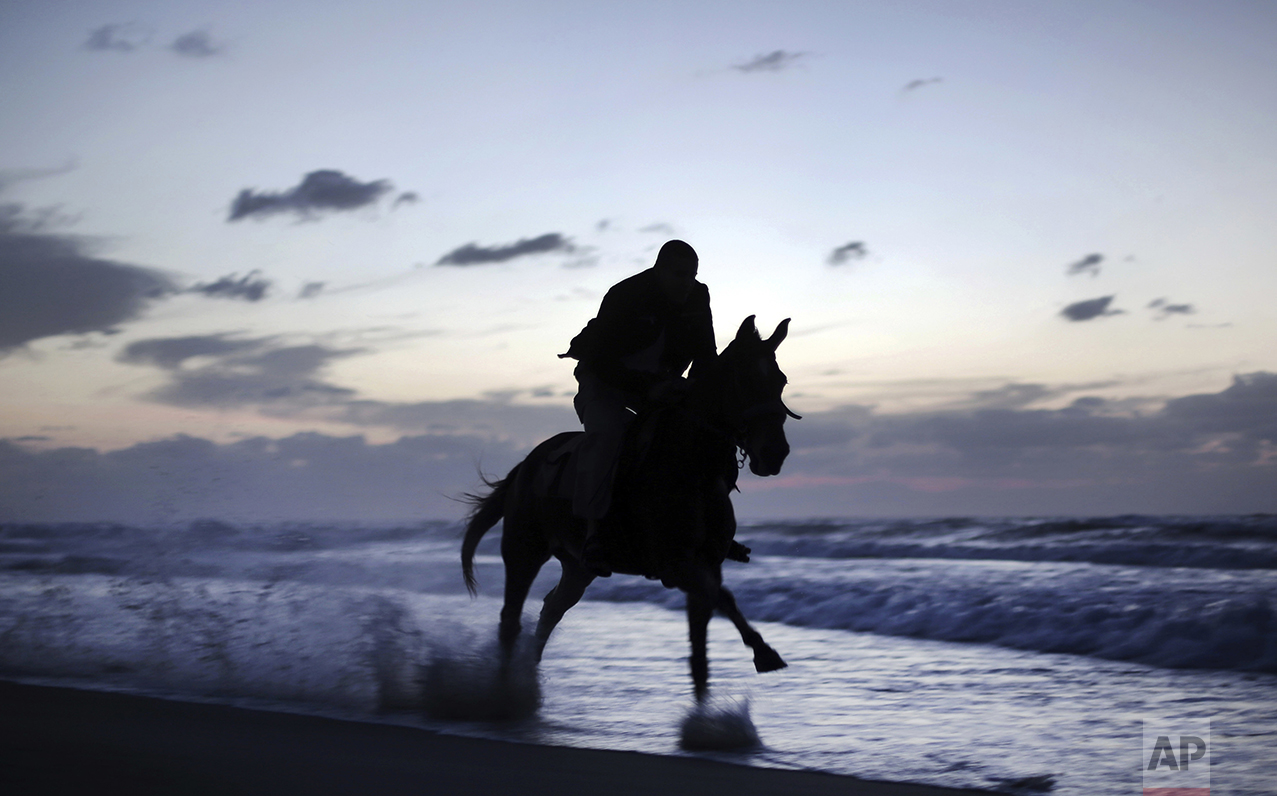 A Palestinian man rides a horse on the beach as the sun sets over Gaza City, Thursday, Nov. 17, 2016. (AP Photo/ Khalil Hamra)