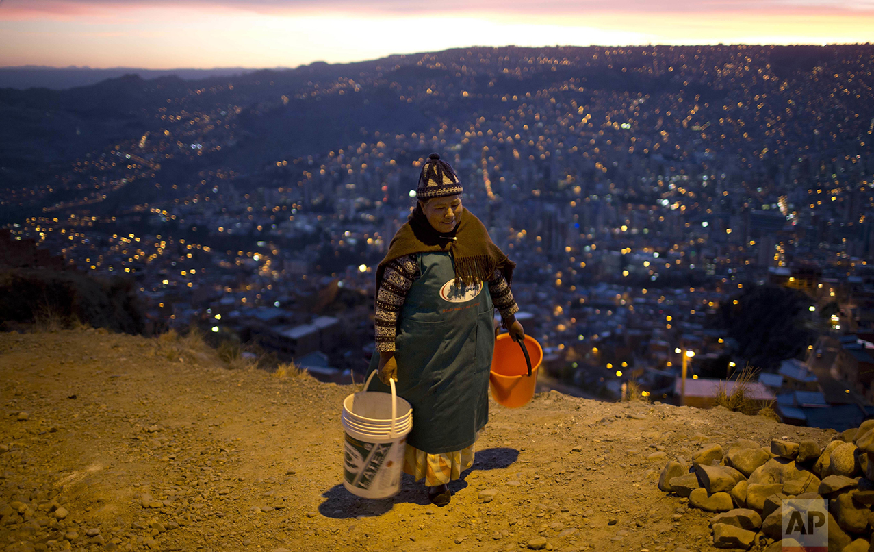  A woman walks with two buckets to wait for a water tank to arrive near her neighborhood in La Paz, Bolivia, Wednesday, Nov. 16, 2016. Bolivia's President Evo Morales asked for forgiveness from residents of the city for water shortages caused by the 