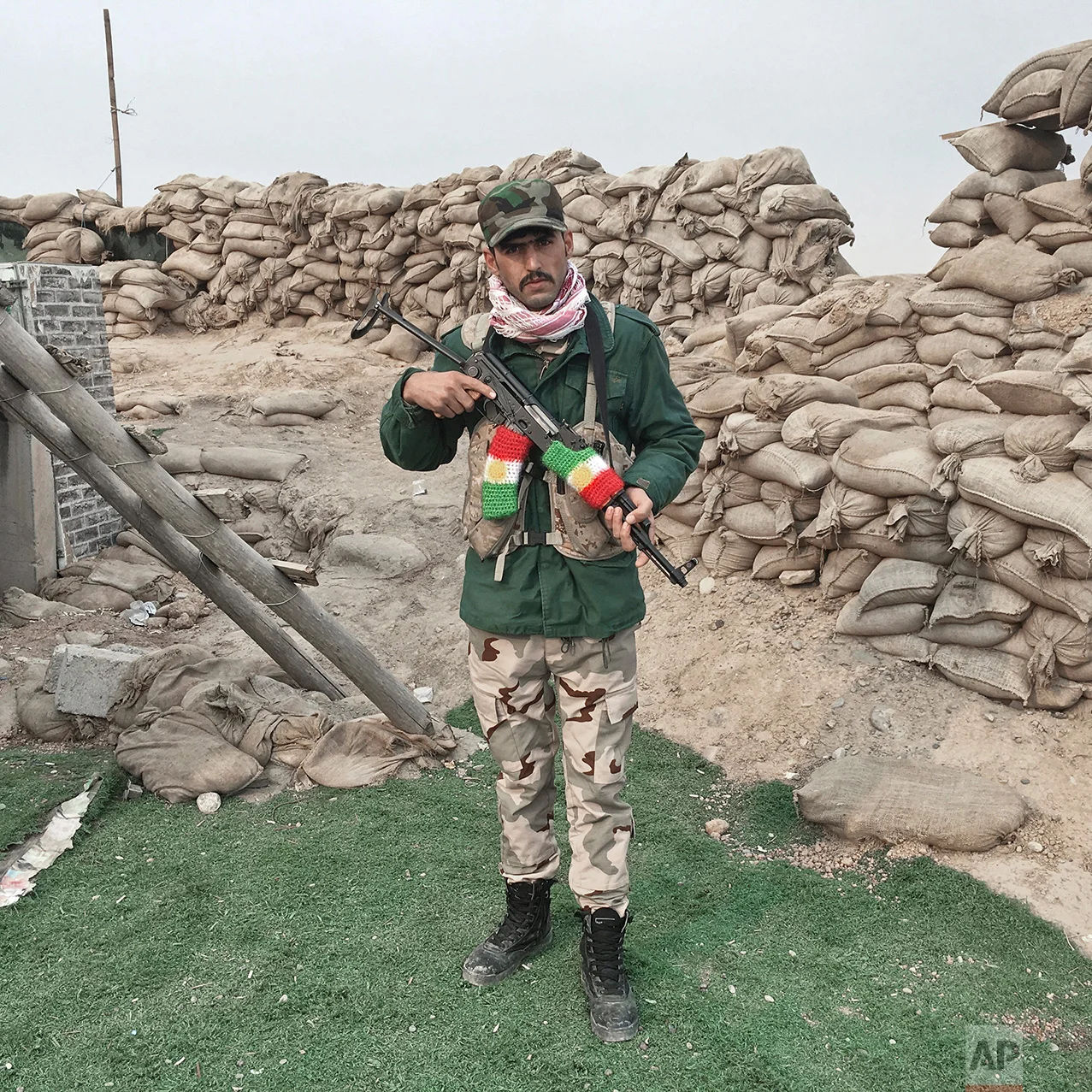In this photo taken Monday, Oct. 24, 2016, Hiwa Omar, 25, from Irbil, Iraq, a Kurdish Peshmerga soldier, poses for a portrait while guarding a checkpoint in Gwer, some 30 kilometers southeast of Mosul, Iraq. The push to kick the Islamic State out of Mosul has brought together an eclectic mix of Iraqis, young and old, police and soldiers, and a variety of irregular uniforms and equipment. (AP Photo/Marko Drobnjakovic)