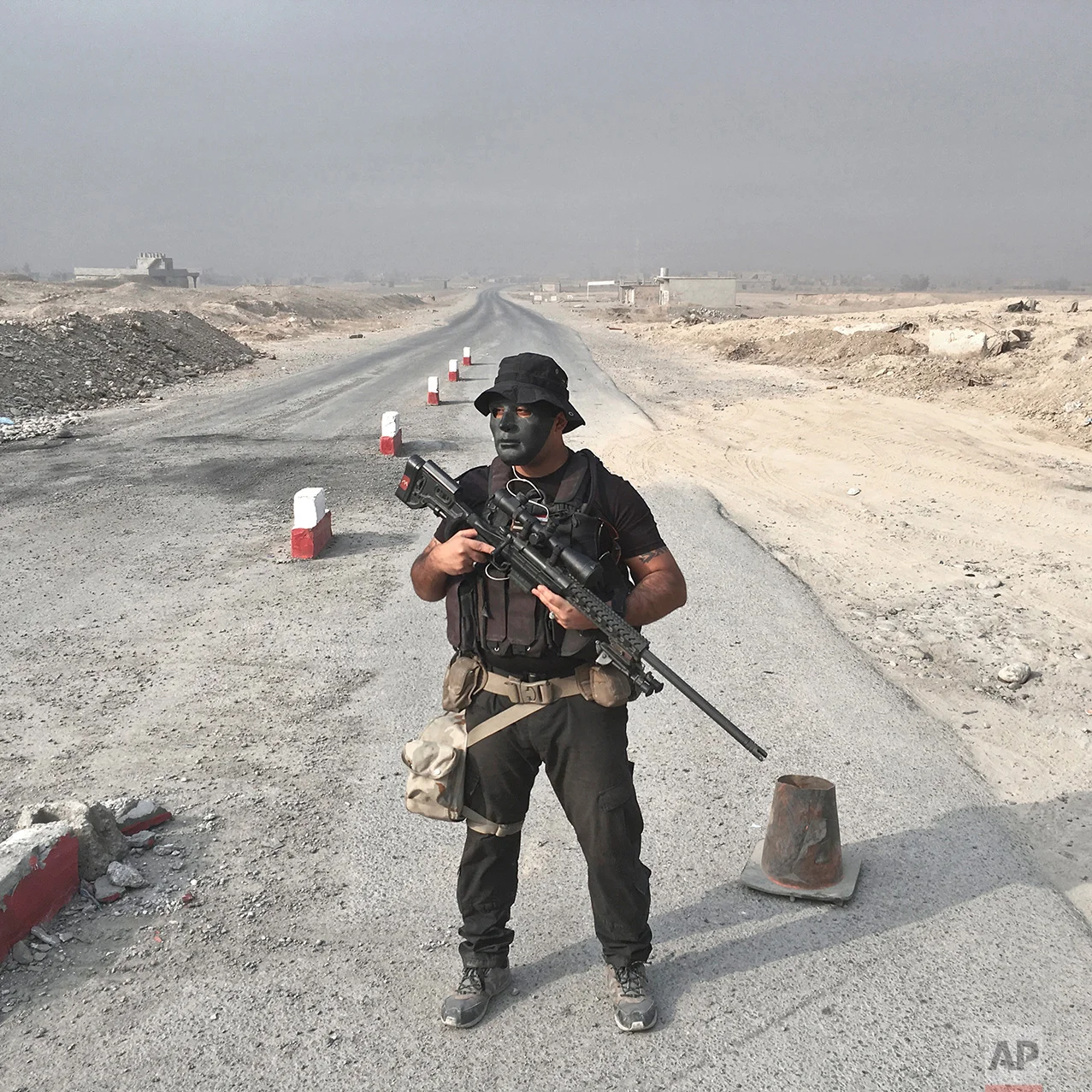 In this photo taken Wednesday, Oct. 26, 2016, Riyad Jaffar, 27, from Baghdad, an Iraqi army sniper, poses for a portrait at a checkpoint on the outskirts of Qayara, some 50 kilometers south of Mosul, Iraq. The push to kick the Islamic State out of Mosul has brought together an eclectic mix of Iraqis, young and old, police and soldiers, and a variety of irregular uniforms and equipment. (AP Photo/Marko Drobnjakovic)