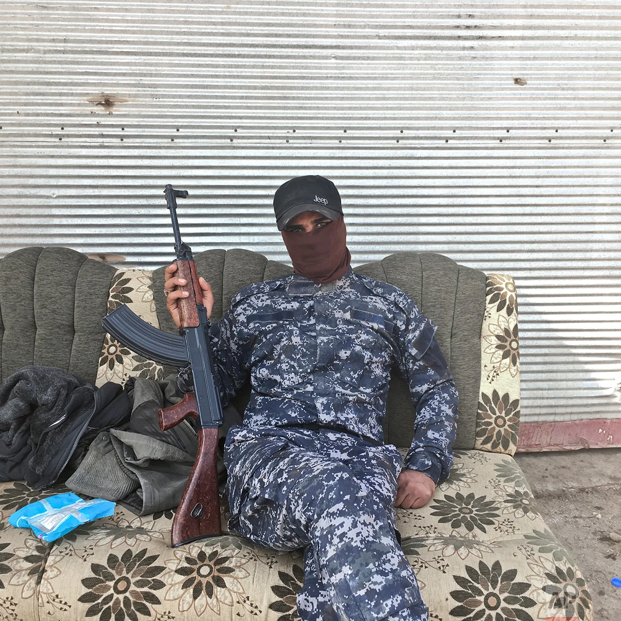 In this photo taken Thursday, Oct. 27, 2016, Abdelyusef, no last name given, an Iraqi Federal Police officer, poses for a portrait at a checkpoint in the village of Al Hut, some 40 kilometers south of Mosul, Iraq. The push to kick the Islamic State out of Mosul has brought together an eclectic mix of Iraqis, young and old, police and soldiers, and a variety of irregular uniforms and equipment. (AP Photo/Marko Drobnjakovic)