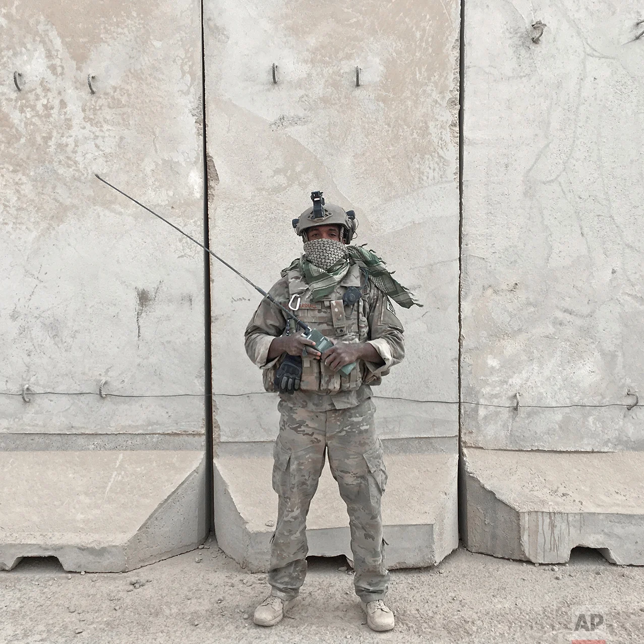 In this photo taken Friday, Oct. 28, 2016, US Air Force Senior Airman Dennis Marshall, 26, from Memphis, Tenn., poses for a portrait while holding his radio at the Qayara West Coalition base in Qayara, some 50 kilometers south of Mosul, Iraq. The push to kick the Islamic State out of Mosul has brought together an eclectic mix of Iraqis, young and old, police and soldiers, and a variety of irregular uniforms and equipment. (AP Photo/Marko Drobnjakovic)