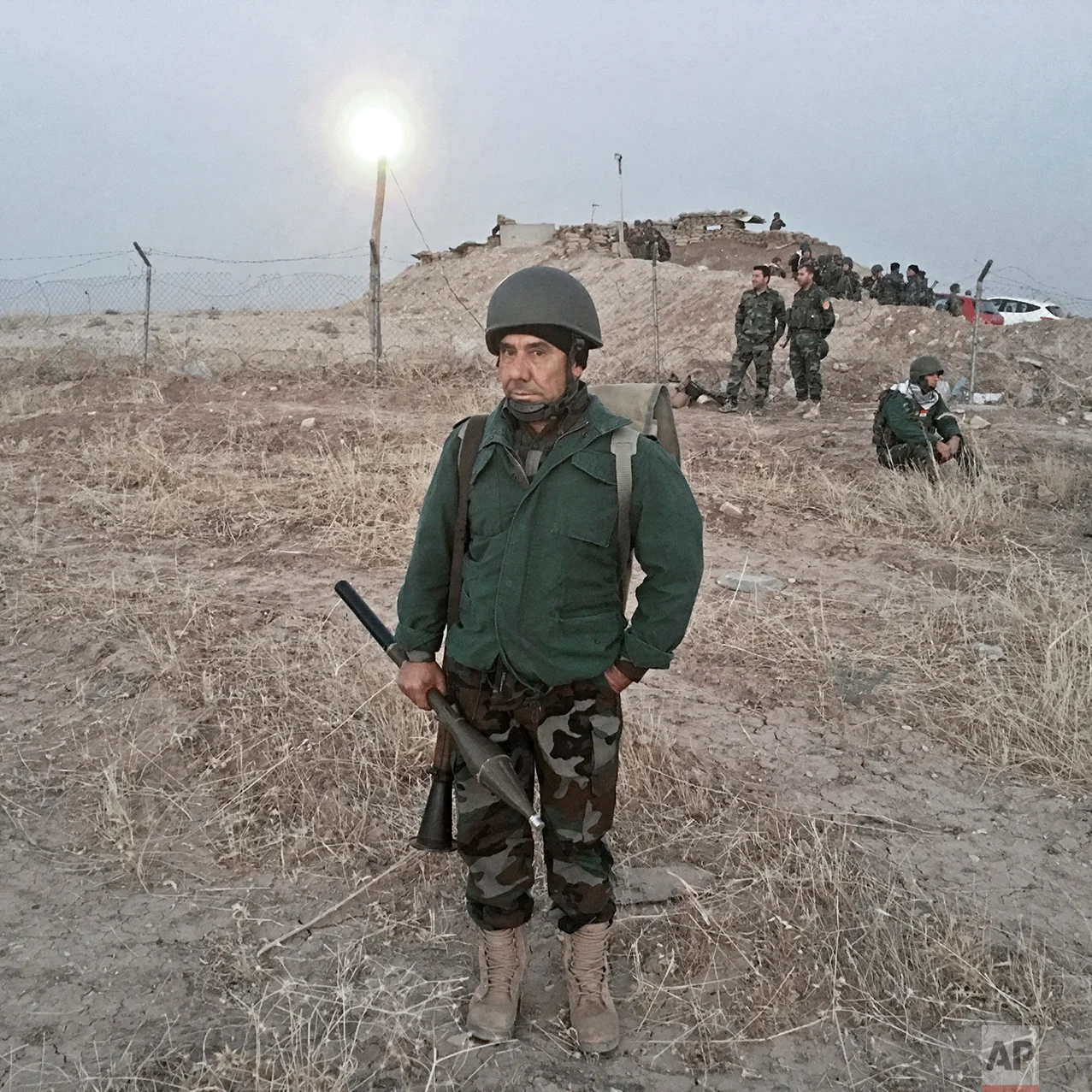 In this photo taken Thursday, Oct. 20, 2016, a Kurdish Peshmerga soldier, no name given, poses for a portrait in Nawaran, some 20 kilometers northeast of Mosul, Iraq. The push to kick the Islamic State out of Mosul has brought together an eclectic mix of Iraqis, young and old, police and soldiers, and a variety of irregular uniforms and equipment. (AP Photo/Marko Drobnjakovic)
