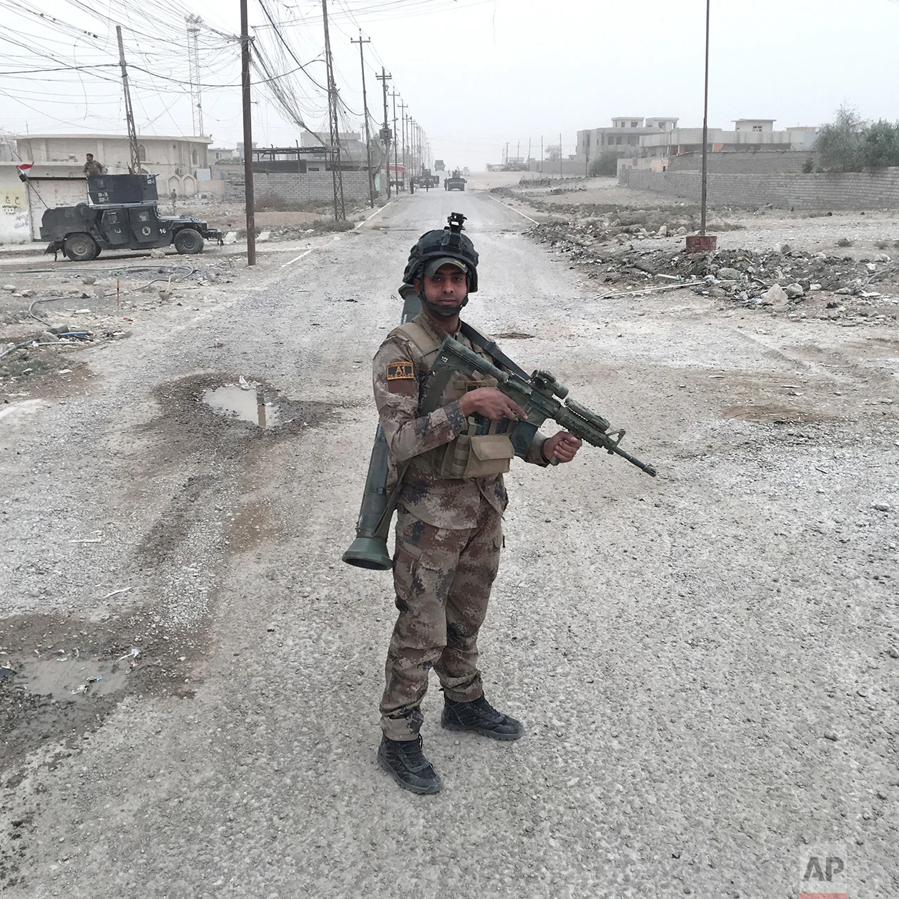 In this photo taken Tuesday, Nov. 1, 2016, Bergam Kadhim, from Najaf, Iraq, an Iraqi Special Forces soldier, poses for a portrait on a street in Gogjali, an eastern suburb of Mosul, Iraq. The push to kick the Islamic State out of Mosul has brought together an eclectic mix of Iraqis, young and old, police and soldiers, and a variety of irregular uniforms and equipment. (AP Photo/Marko Drobnjakovic)