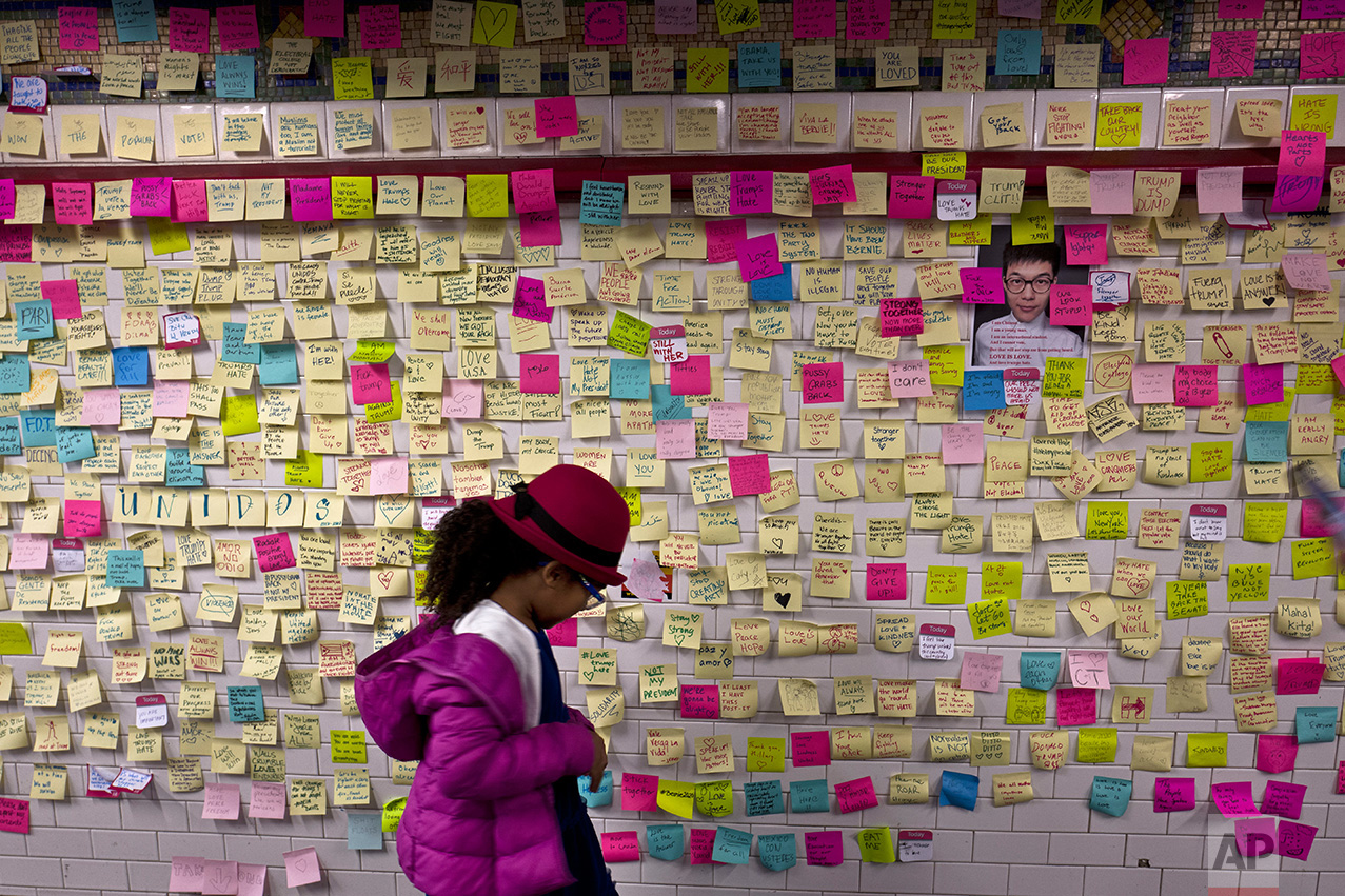 In this Sunday, Nov. 13, 2016 photo, a girl looks at anti- President-elect Donald Trump notes placed on a wall in the Union Square Subway Station in New York. (AP Photo/Muhammed Muheisen)