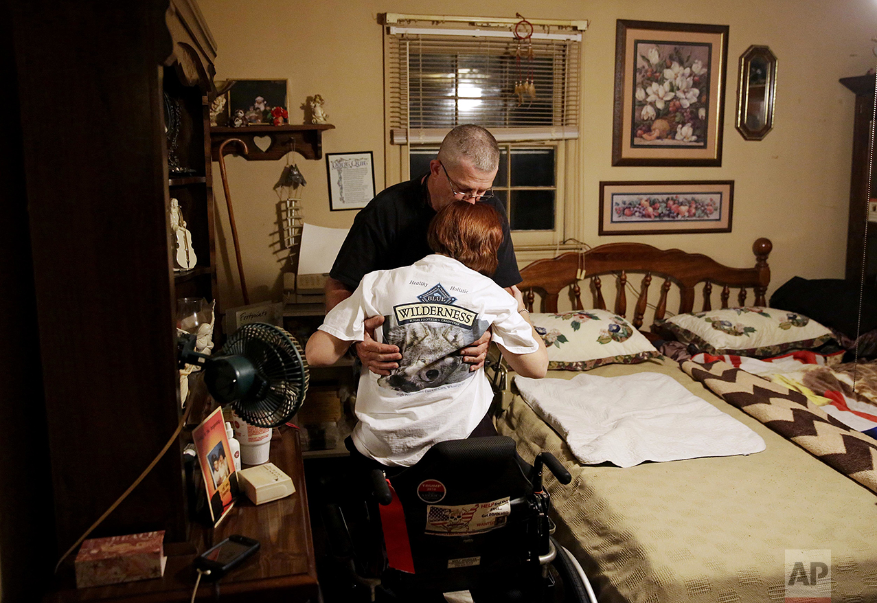 Billy Inman kisses the forehead of his wife, Kathy, as he lifts her out of her wheelchair to help her into bed at their home Friday, May 27, 2016, in Woodstock, Ga. In 2000, a Mexican national in the country illegally crashed his vehicle into one driven by Billy who had stopped for a red light. The impact killed the Inman's 16-year-old son, Dustin, and the family dog and left Kathy with serious injuries. Since then, the Inmans have become involved in seeking stricter enforcement of laws to combat illegal immigration. "I miss the hugs. I always got a hug from my son before going to bed," said Billy. "Breaks my heart he's been gone 16 years and nothing else has been done. His killer is still walking around. It's not right." (AP Photo/David Goldman)