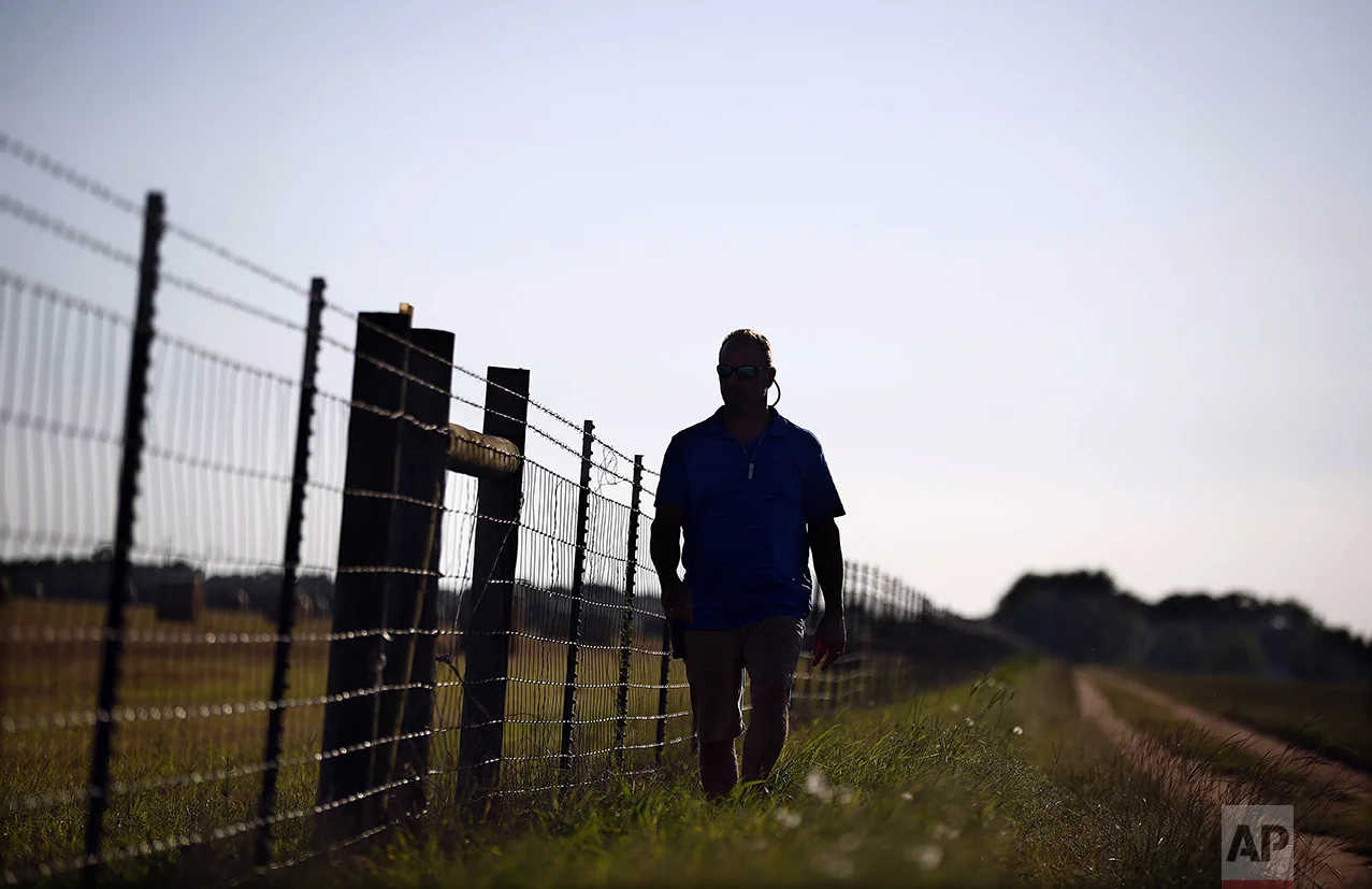 John Lazzari Jr., 47, walks along a path on the Naval Outlying Field Silverhill base next to his home in Daphne, Ala., on Thursday, June 23, 2016. Government officials are deciding whether to put an undocumented, unaccompanied children's camp at the site. Lazzari says that he worries about the safety of his family. "I'm against the refugees coming next to my home because of the unknown, what if they are terrorists or violent youth? Everything I hear about the refugees is bad. I want my family safe." Lazzari says. (AP Photo/Brynn Anderson)