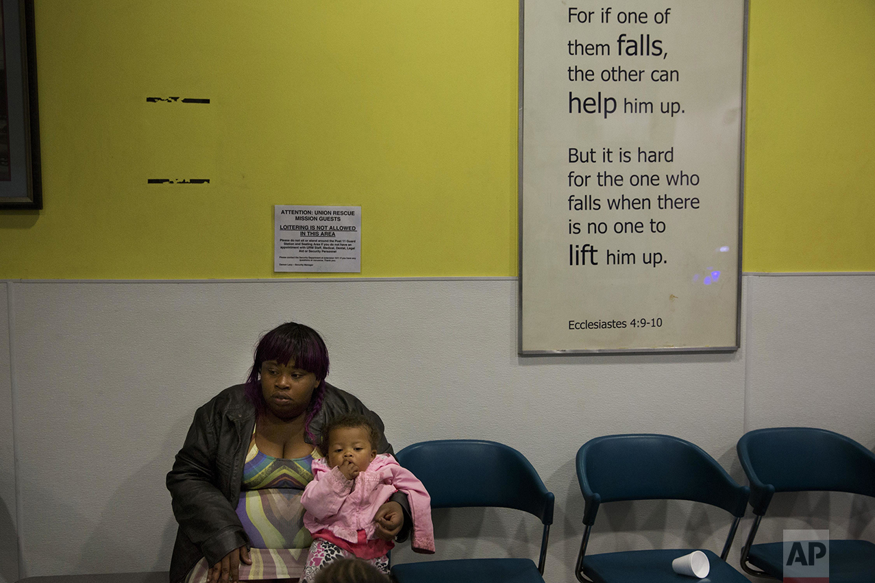 Mariah Griffin-Hernandez, 25, sits with her 1-year-old daughter, Xy-lena, as she waits for her husband, James, in the lobby of the Union Rescue Mission in Los Angeles on Thursday, May 5, 2016. Originally from Houston, they moved to California this year with their two daughters to try to find a better future for their family. They want to make enough money to rent a small apartment, but at the moment, they're staying at a family shelter on Skid Row. "Being homeless is very depressing. I feel like I couldn't take care of my family, but also being on Skid Row is very depressing, looking at all these people out here addicted to drugs," said James. (AP Photo/Jae C. Hong)