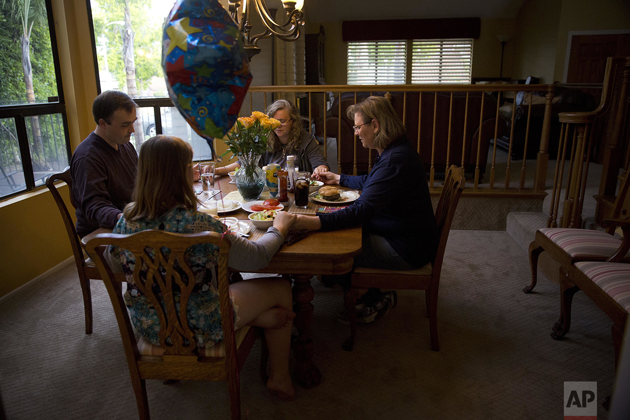 Karen Fagan, right, and husband, Ian, hold hands with Karen's two daughters, Kate and Elizabeth Bowman as they pray to celebrate Elizabeth's birthday in Upland, Calif., on Saturday, May 7, 2016. Fagan's ex-husband, Harry Bowman, the father of her two daughters, was killed in the previous year's terrorist attack in San Bernardino, Calif. But the tragic event didn't change her beliefs, and she began participating in interfaith community events. Fagan still thinks that the county should accept Muslim refugees. "America is full of lots of different people from lots of different places," said Fagan. "It saddens me that America is no longer the place where people can come to escape oppression... It's our obligation as Americans and Christians." (AP Photo/Jae C. Hong)