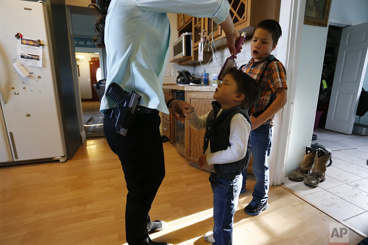 Gun-rights advocate, restaurant owner and mother of four sons Lauren Boebert wears her usual gun on her hip as she brushes the hair of Roman, 3, as the family gets ready to leave home for church in Rifle, Colo., on May 1, 2016. "When we first opened Shooters Grill, we were one month in, and I was there alone a lot, and there was actually a man who was beat to death in the alley. He lost his life that night, and it kinda shook me up. I was there alone a lot and I thought, 'what am I gonna do, what am I gonna do if something happens, what if somebody comes in here, my husband isn't here to protect me, I'm all alone,' and really, that's what got me to open-carry." (AP Photo/Brennan Linsley)