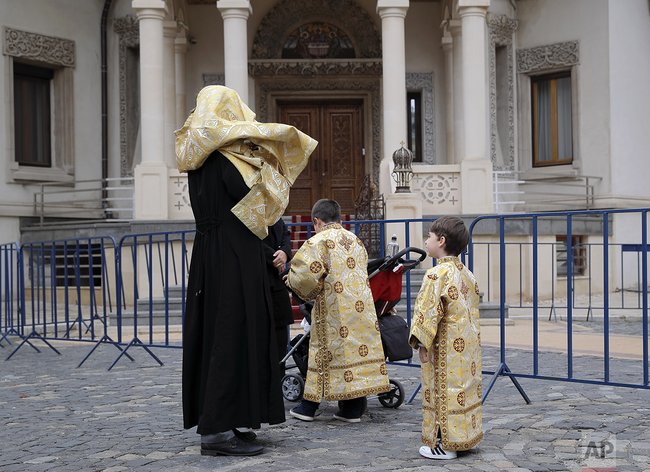  In this Saturday, Oct. 22, 2016 picture, children wearing orthodox priest outfits watch a priest getting into his outfit in Bucharest, Romania. The feast of St. Dimitrie of Basarobov in Bucharest is an annual demonstration of the strength of Christi