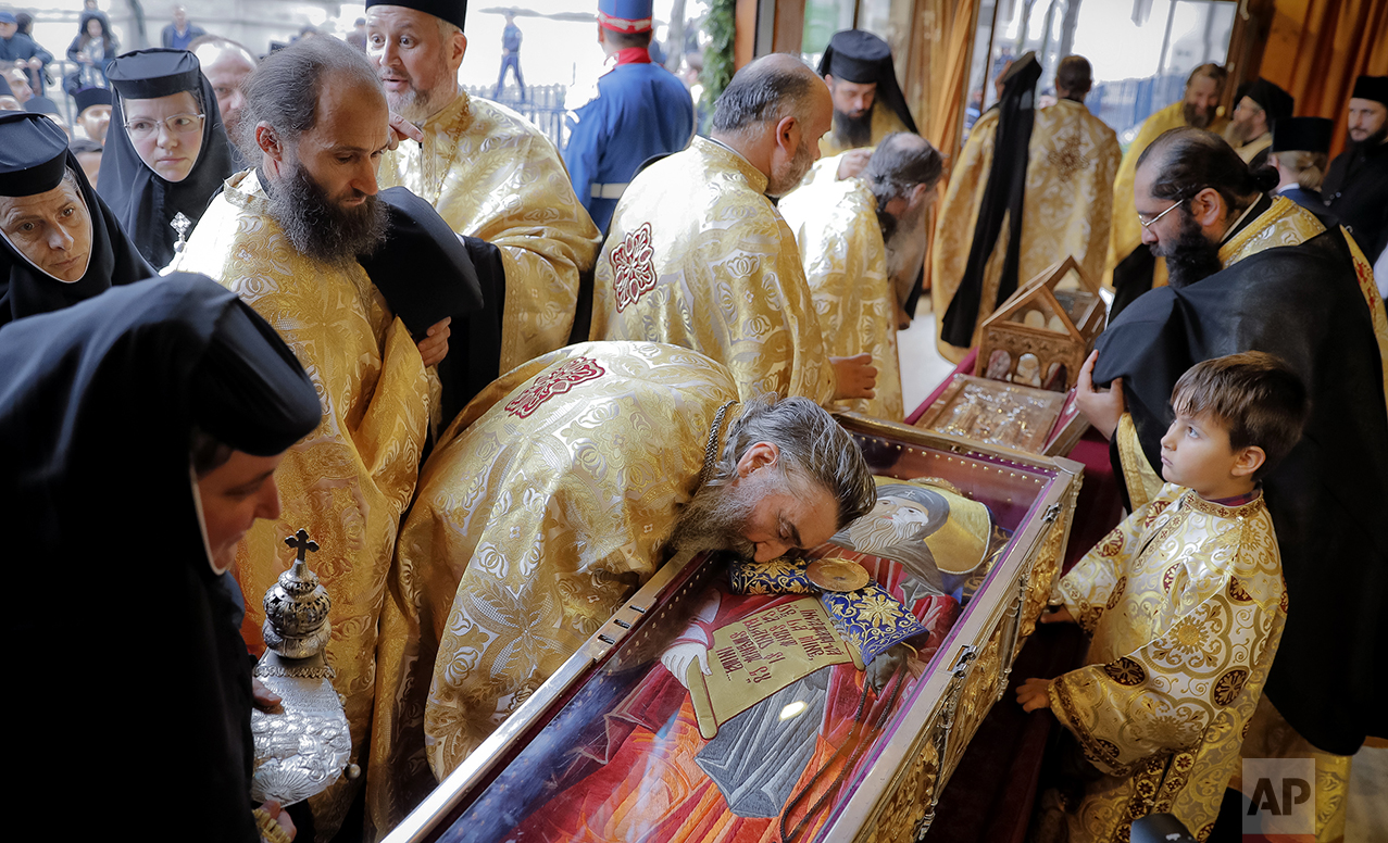  In this Saturday, Oct. 22, 2016 picture, a child watches as a priest leans on a container holding the remains of Saint Dimitrie Bassarabov, as other clerics wait for their turn, during a pilgrimage, in Bucharest, Romania. (AP Photo/Vadim Ghirda) 
