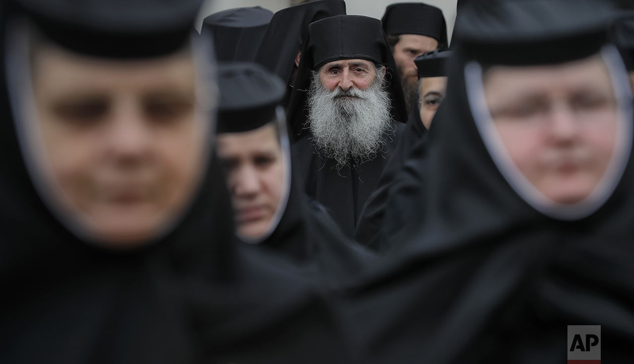  In this Saturday, Oct. 22, 2016 picture, Orthodox nuns and priests wait before a pilgrimage, in Bucharest, Romania. Both churches parade holy remains. The Catholics have a few drops of the blood of Saint John Paul II; the Orthodox claim to have the 