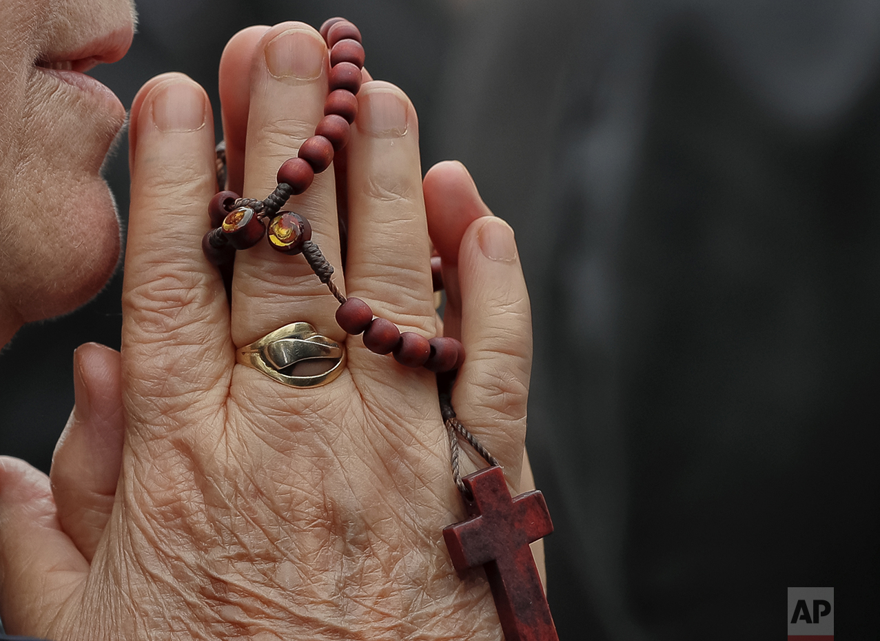  In this Sunday, Oct. 23, 2016 picture, a Catholic worshiper prays during a pilgrimage with Pope John Paul II's remains, in Bucharest, Romania. Both churches parade holy remains. The Catholics have a few drops of the blood of Saint John Paul II; the 