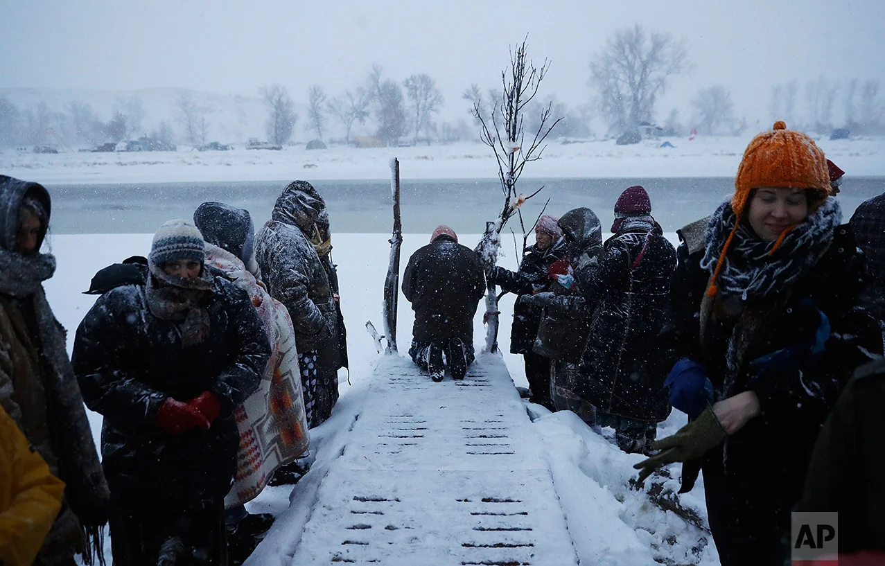 In this Tuesday, Nov. 29, 2016 photo, a person prays along the Cannonball River during a Native American water ceremony at the Oceti Sakowin camp where people have gathered to protest the Dakota Access oil pipeline in Cannon Ball, N.D. So far, those fighting the Dakota Access pipeline have shrugged off the heavy snow, icy winds and frigid temperatures that have swirled around their large encampment on the North Dakota grasslands. (AP Photo/David Goldman)