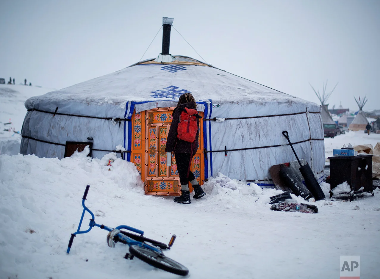 In this Thursday, Dec. 1, 2016 photo, a student walks into the school at the Oceti Sakowin camp where people have gathered to protest the Dakota Access pipeline near Cannon Ball, N.D. The school teaches on average 20 students a day in the traditional Lakota curriculum as well as math, reading and writing. (AP Photo/David Goldman)