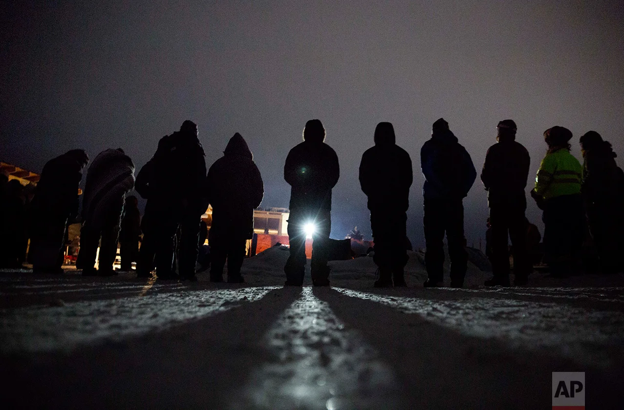In this Wednesday, Nov. 30, 2016 photo, people form a circle for the morning prayer at the Oceti Sakowin camp where many have gathered to protest the Dakota Access pipeline near Cannon Ball, N.D. The number of inhabitants has ranged from several hundred to several thousand. It has been called the largest gathering of Native American tribes in a century. (AP Photo/David Goldman)