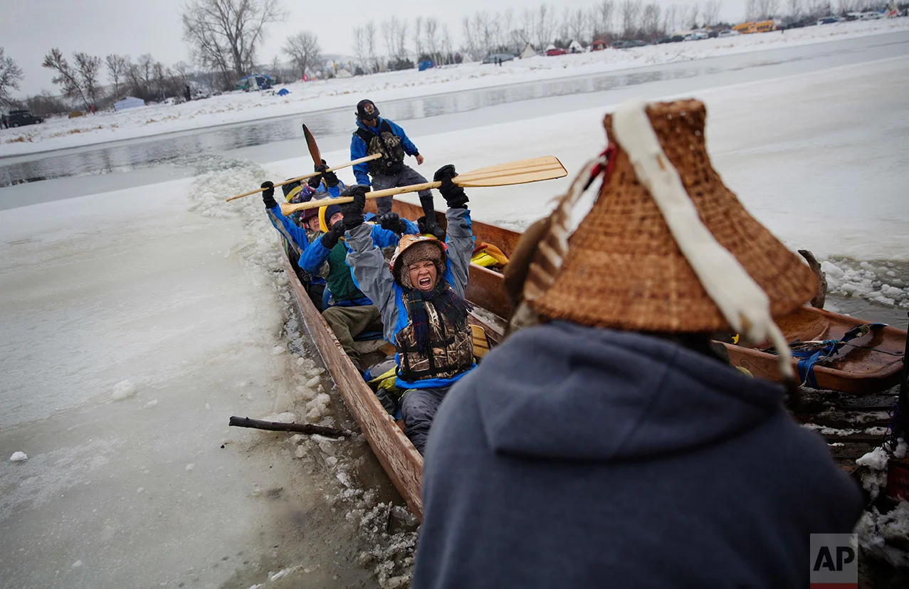 In this Thursday, Dec. 1, 2016 photo, Virginia Redstar of Colville, Wash., and a member of the Colville Native American tribe, celebrates upon reaching shore by canoe at the Oceti Sakowin camp where people have gathered to protest the Dakota Access oil pipeline in Cannon Ball, N.D. Redstar traveled from Montana with fellow tribal members on canoe for 10 days down the Missouri river to reach the camp. (AP Photo/David Goldman)