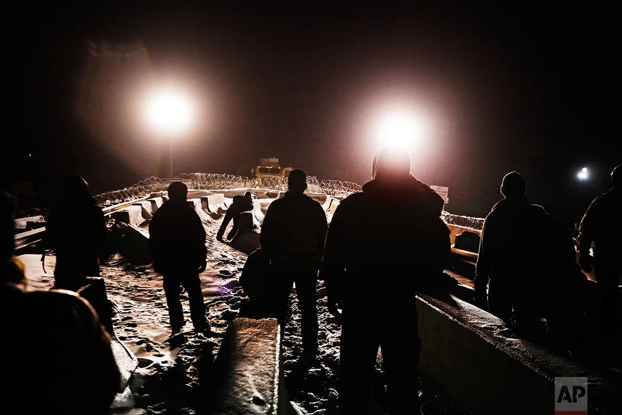 In this Thursday, Dec. 1, 2016 photo, military veterans walk onto a closed bridge to protest across from police protecting the Dakota Access oil pipeline site in Cannon Ball, N.D. More than 525 people from across the country have been arrested since August. In a recent clash between police and protesters near the path of the pipeline, officers used tear gas, rubber bullets and large water hoses in sub-freezing temperatures. (AP Photo/David Goldman)
