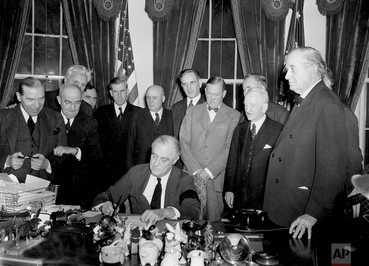 U.S. President Franklin D. Roosevelt signs the declaration of war following the Japanese bombing of Pearl Harbor, Dec. 7, at the White House in Washington, D.C., Dec. 8, 1941 at 3:08 p.m. EST. Watching from left to right are, Rep. Sol Bloom, D-N.Y.; Rep. Luther Johnson, D-Texas; Rep. Charles A. Eaton, R-N.J.; Rep. Joseph Martin, R-Mass.; Vice President Henry A. Wallace; House Speaker Sam Rayburn, D-Texas; Rep. John McCormack, D-Mass.; Sen. Charles L. McNary, R-Ore.; Sen. Alben W. Barkley, D-Ky.; Sen. Carter Glass, D-Va.; and Sen. Tom Connally, D-Texas. (AP Photo)