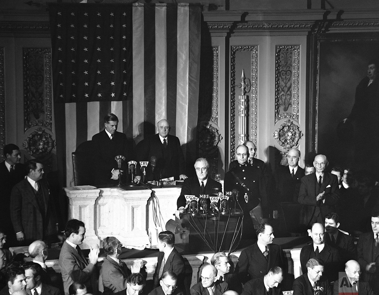 Declaring Japan guilty of a dastardly unprovoked attack, President Franklin D. Roosevelt asked Congress to declare war, Dec. 8, 1941. Listening are Vice President Henry Wallace, left, and House Speaker Sam Rayburn. (AP Photo)