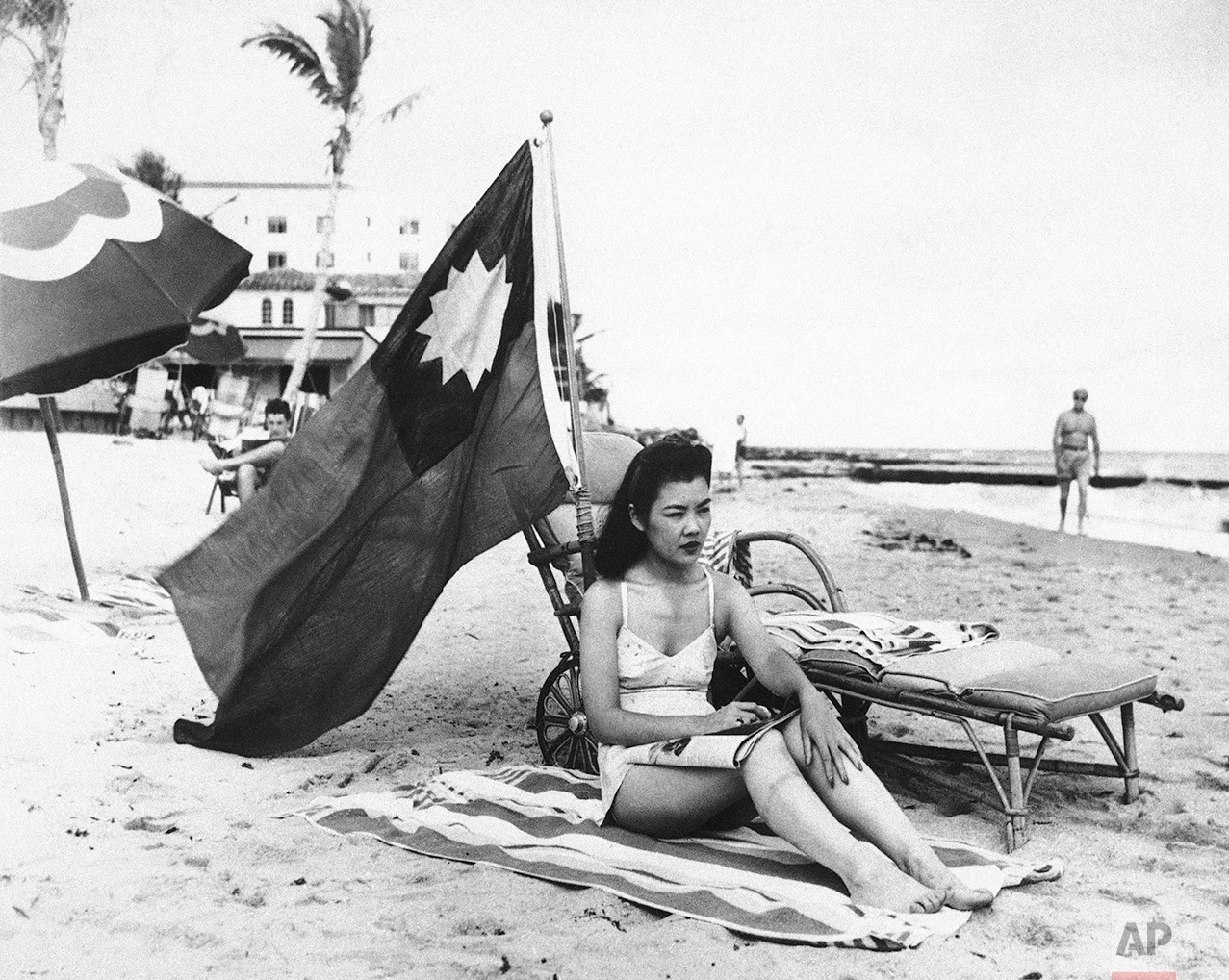 Ruth Lee, hostess at a Miami Chinese restaurant, seen Dec. 15, 1941, doesn't want to be mistaken for Japanese when she sunbathes on her days off, and brings along a Chinese flag. Miss Lee is actually American-born. (AP Photo)