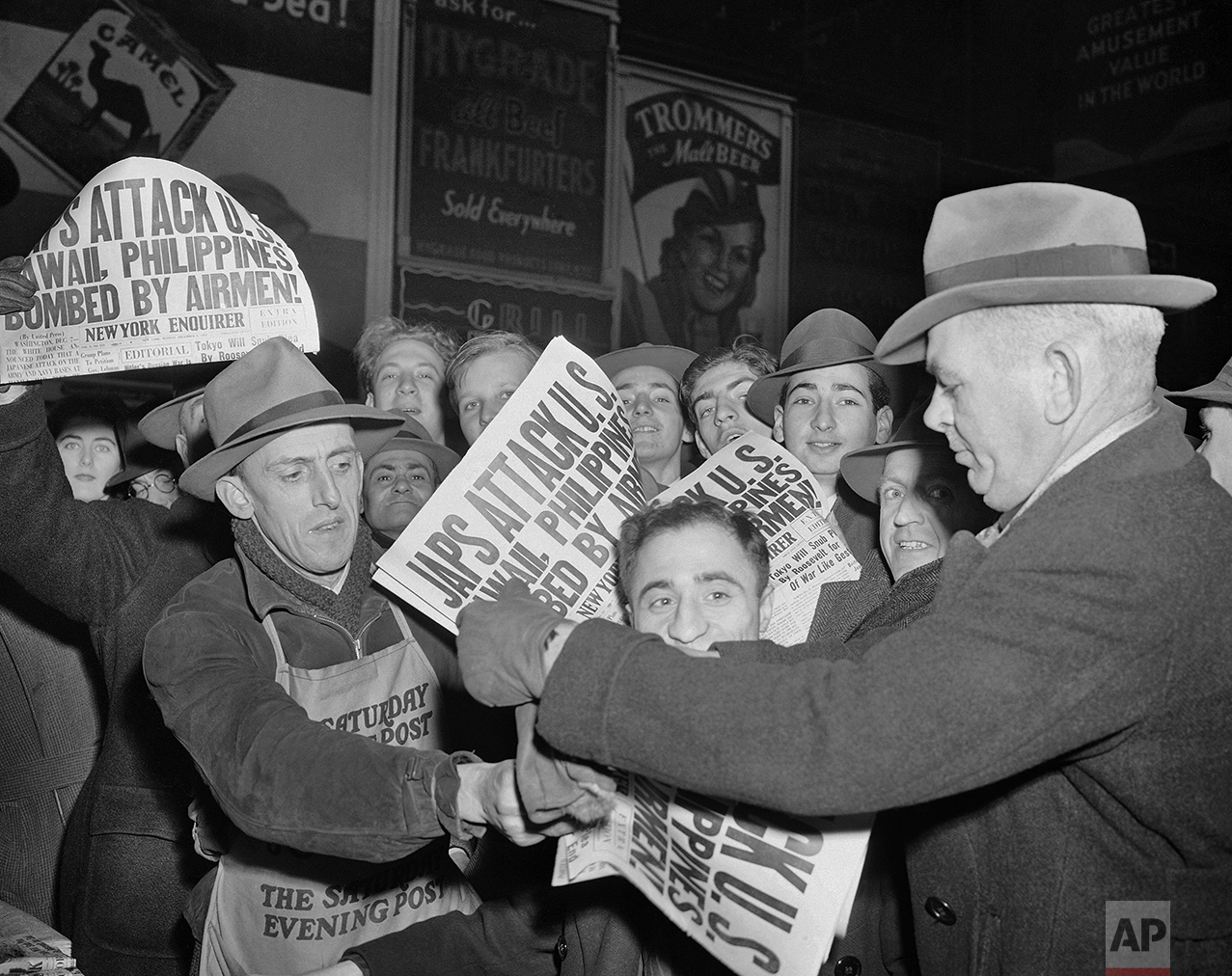 In this Dec. 7, 1941 photo, people buy newspapers reporting the Japanese attack on U.S. bases in the Pacific Ocean, at Times Square in New York. (AP Photo/Robert Kradin)