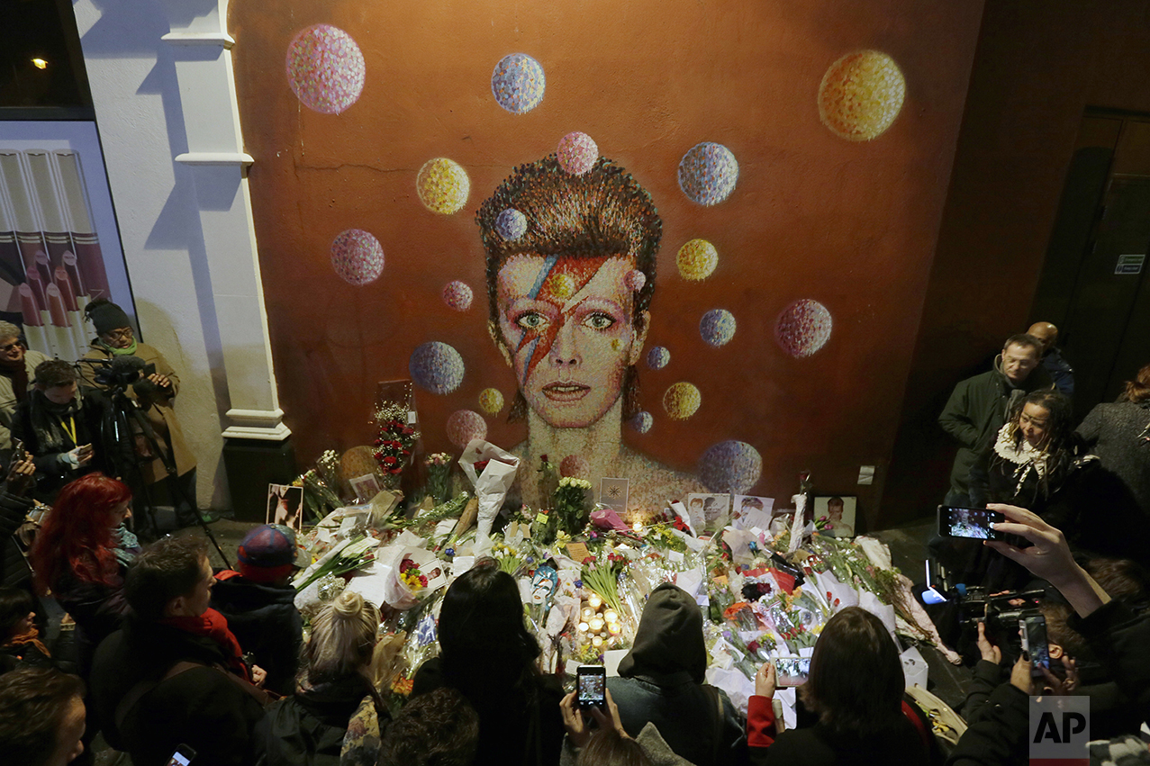  People gather next to tributes placed near a mural of British singer David Bowie by artist Jimmy C, in Brixton, south London, on Jan. 11, 2016. Bowie, the other-worldly musician who broke pop and rock boundaries with his creative musicianship, nonco