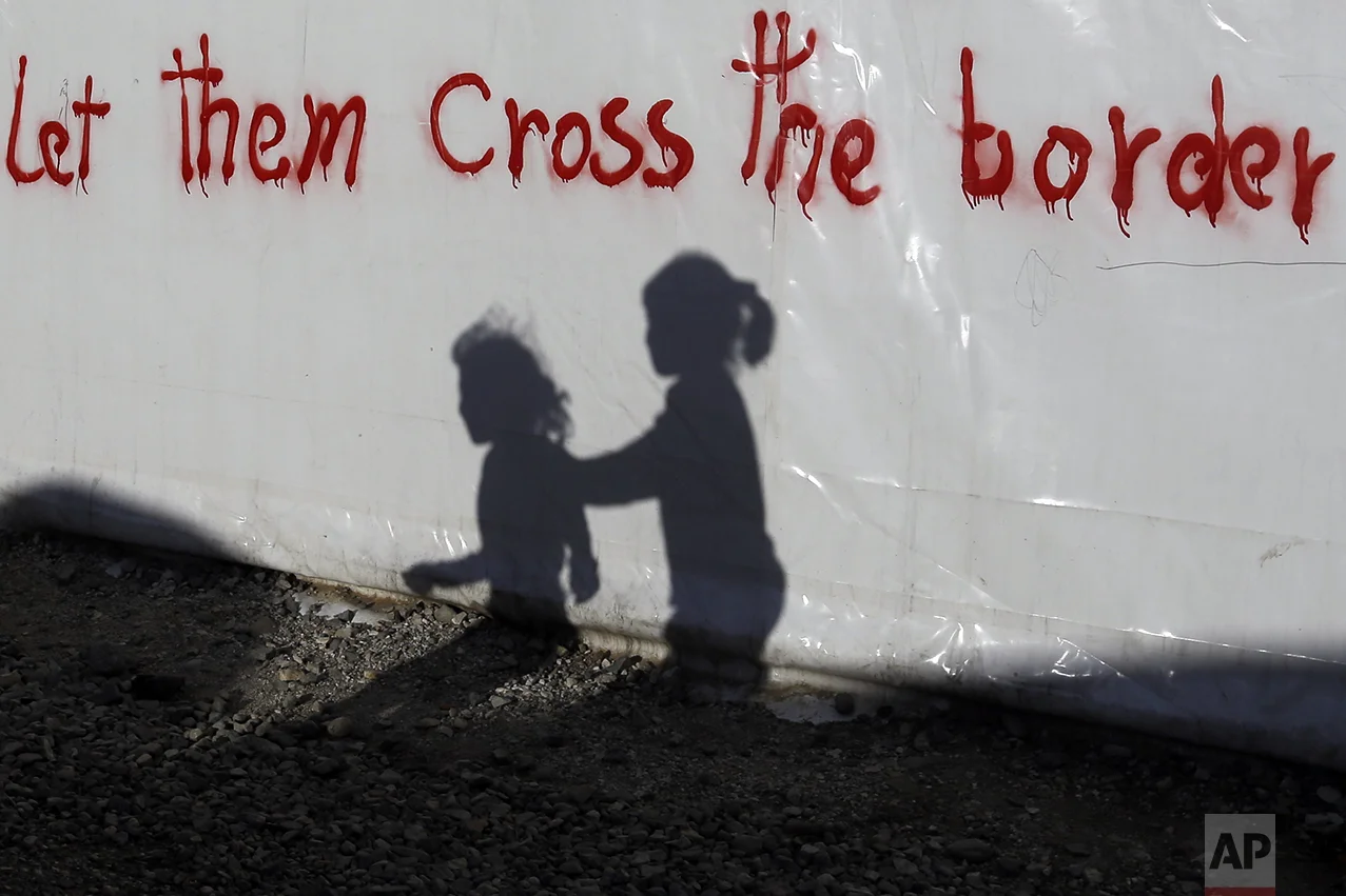 Shadows of children are cast on a tent bearing graffiti at the northern Greek border point of Idomeni, Greece, on May 4, 2016. (AP Photo/Gregorio Borgia)