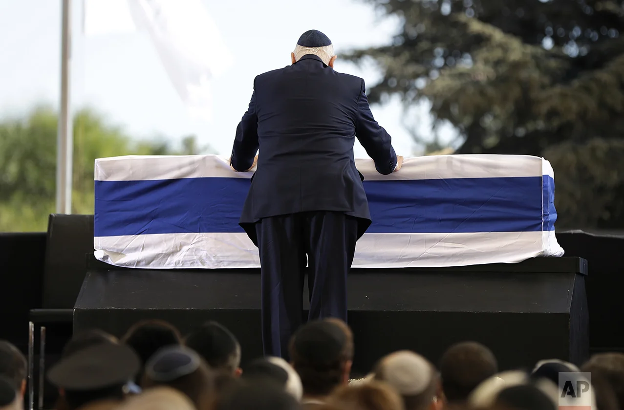 Israeli President Reuven Rivlin places his hands on the casket of former Israeli President Shimon Peres as he takes the stage to speak during a memorial service at Mount Herzl national cemetery in Jerusalem on Sept. 30, 2016. Peres died from complications from a stroke. He was 93. (AP Photo/Carolyn Kaster)