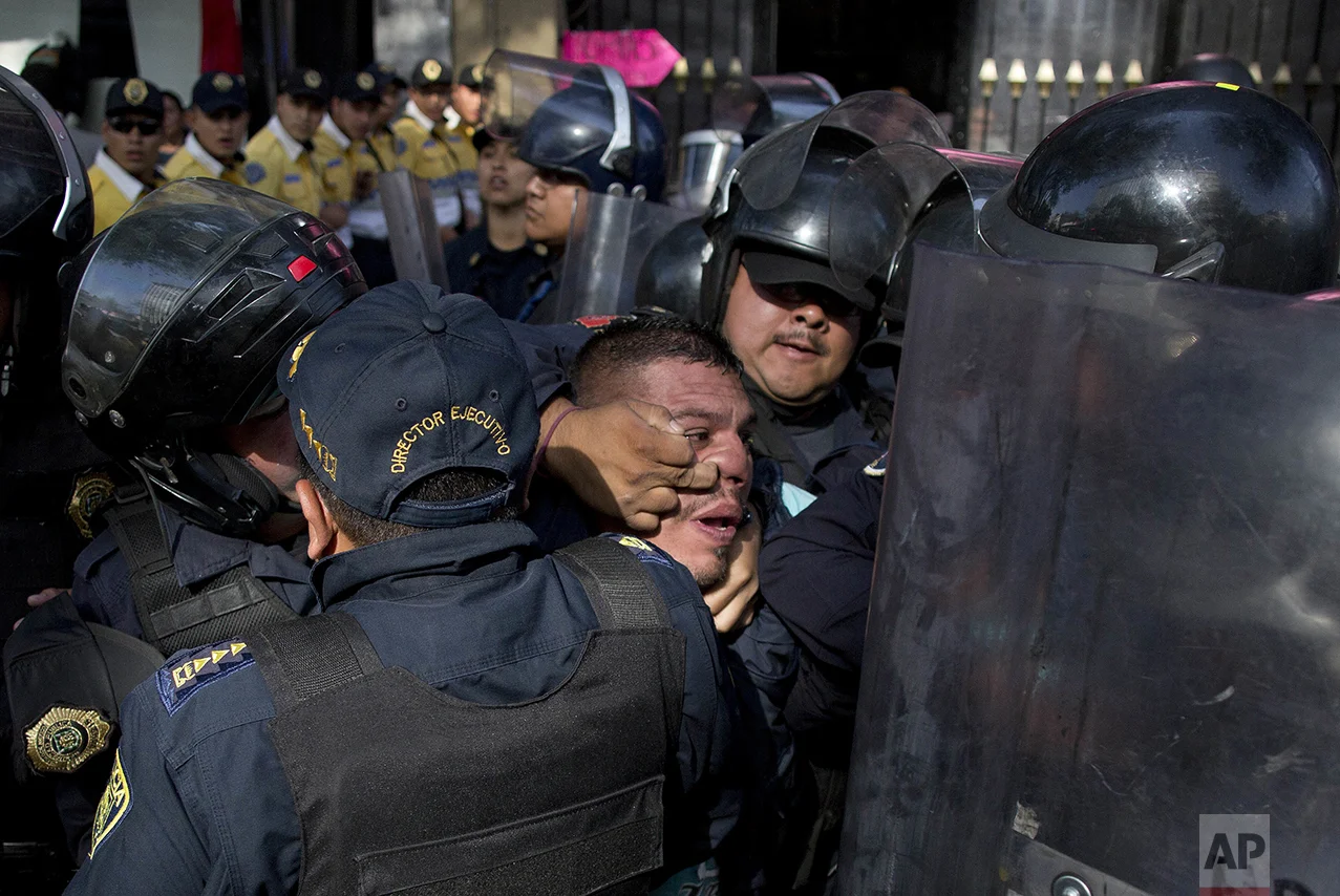 Police detain a taxi driver who, along with other cabbies, blocked a main road to protest the one day per week driving restriction in Mexico City on April 13, 2016. Under new regulations imposed after the capital experienced its worst air-quality crisis in over a decade, 40 percent of cars were ordered temporarily off the road. (AP Photo/Eduardo Verdugo)