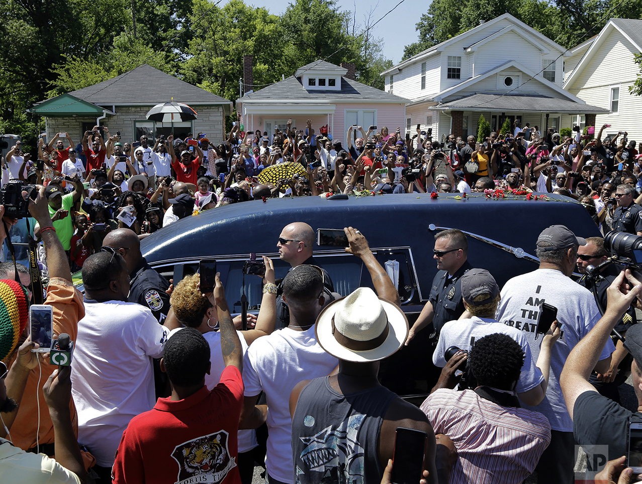  The hearse carrying the body of Muhammad Ali passes in front of his boyhood home, top center, during his funeral procession in Louisville, Ky., on June 10, 2016. Ali, born Cassius Clay, died on June 3 at age 74. (AP Photo/Mark Humphrey) 