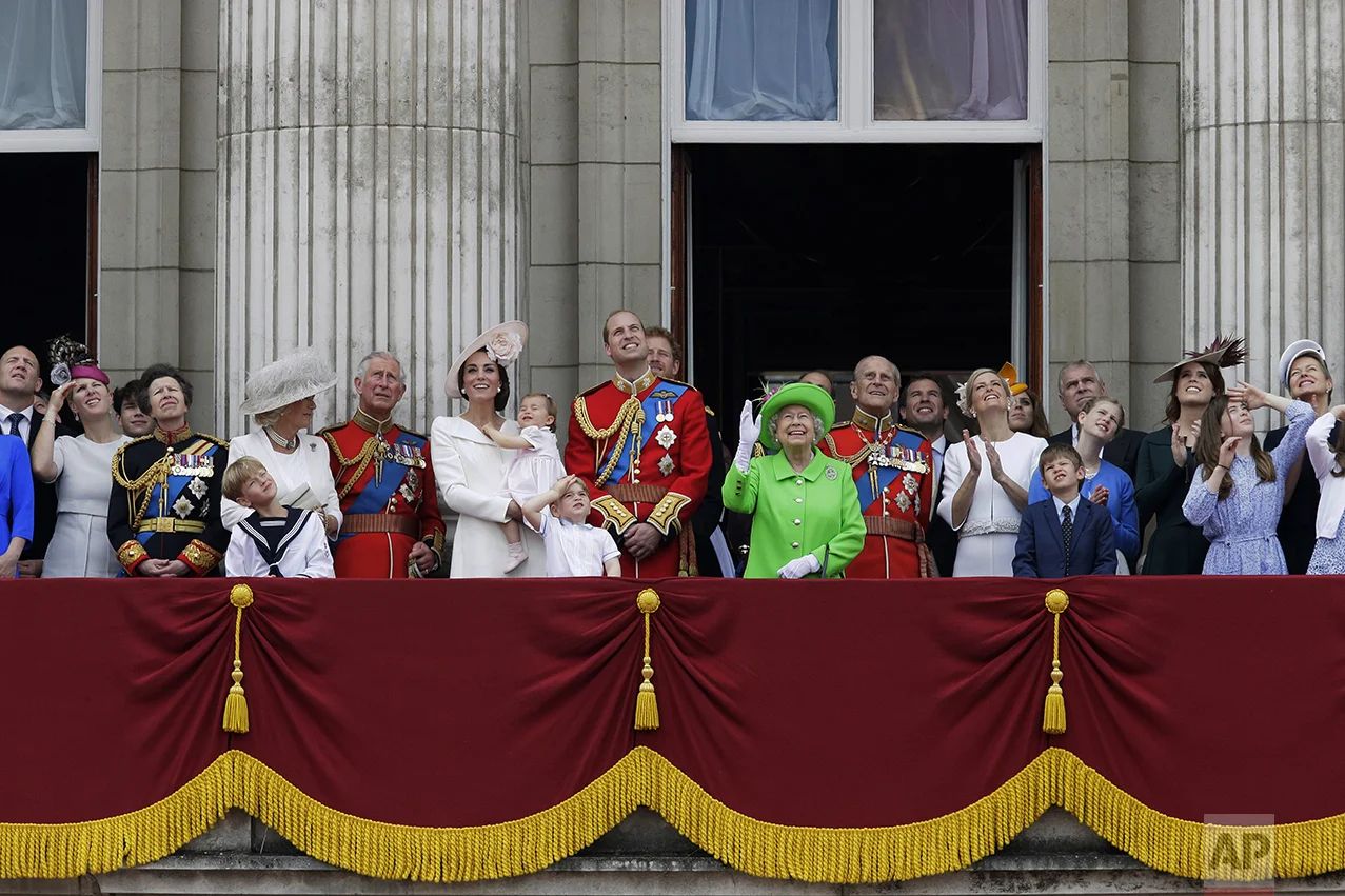 Britain's Queen Elizabeth II waves as she watches the flypast, with Prince Philip, to right, Prince William, centre, with his son Prince George, front, Kate, Duchess of Cambridge holding Princess Charlotte, centre left, with The Prince of Wales standing with The Duchess of Cornwall, and Princess Anne, fourth left, on the balcony during the Trooping The Colour parade at Buckingham Palace, in London, on June 11, 2016. Hundreds of soldiers in ceremonial dress marched in London in the annual parade to mark the official birthday of Queen Elizabeth II. The Trooping the Colour tradition originates from preparations for battle, when flags were carried or "trooped" down the rank for soldiers to see. (AP Photo/Tim Ireland)
