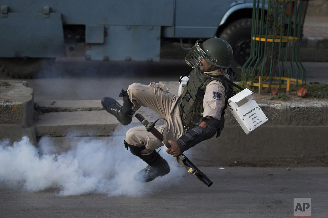  An Indian paramilitary soldier falls as he tries to kick an exploded tear gas shell thrown back by Kashmiri Muslim protesters at the end of a day-long curfew in Srinagar, Indian controlled Kashmir, on Aug. 8, 2016. Kashmir had been under a security 