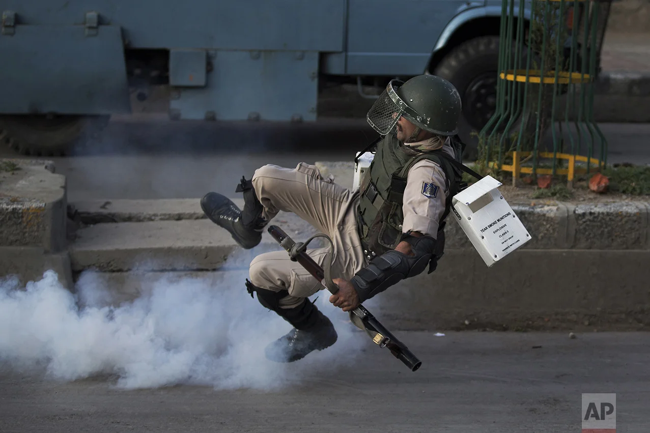 An Indian paramilitary soldier falls as he tries to kick an exploded tear gas shell thrown back by Kashmiri Muslim protesters at the end of a day-long curfew in Srinagar, Indian controlled Kashmir, on Aug. 8, 2016. Kashmir had been under a security lockdown and curfew since the killing of a popular rebel commander on July 8 sparked some of the largest protests against Indian rule in recent years. (AP Photo/Dar Yasin)
