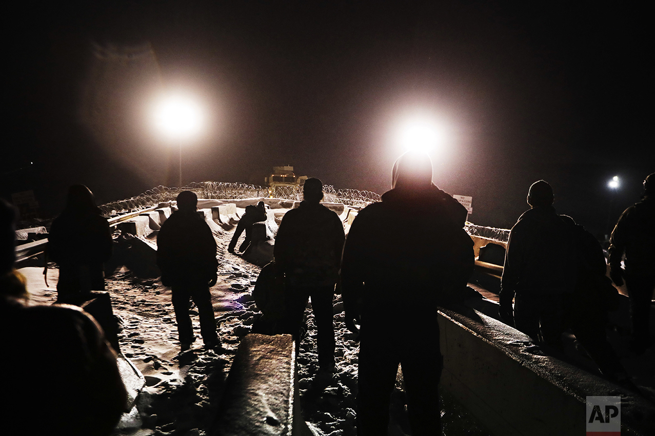  Military veterans walk onto a closed bridge to protest the Dakota Access oil pipeline across from police protecting the site in Cannon Ball, N.D., on Dec. 1, 2016. In a recent clash between police and protesters near the path of the pipeline, office