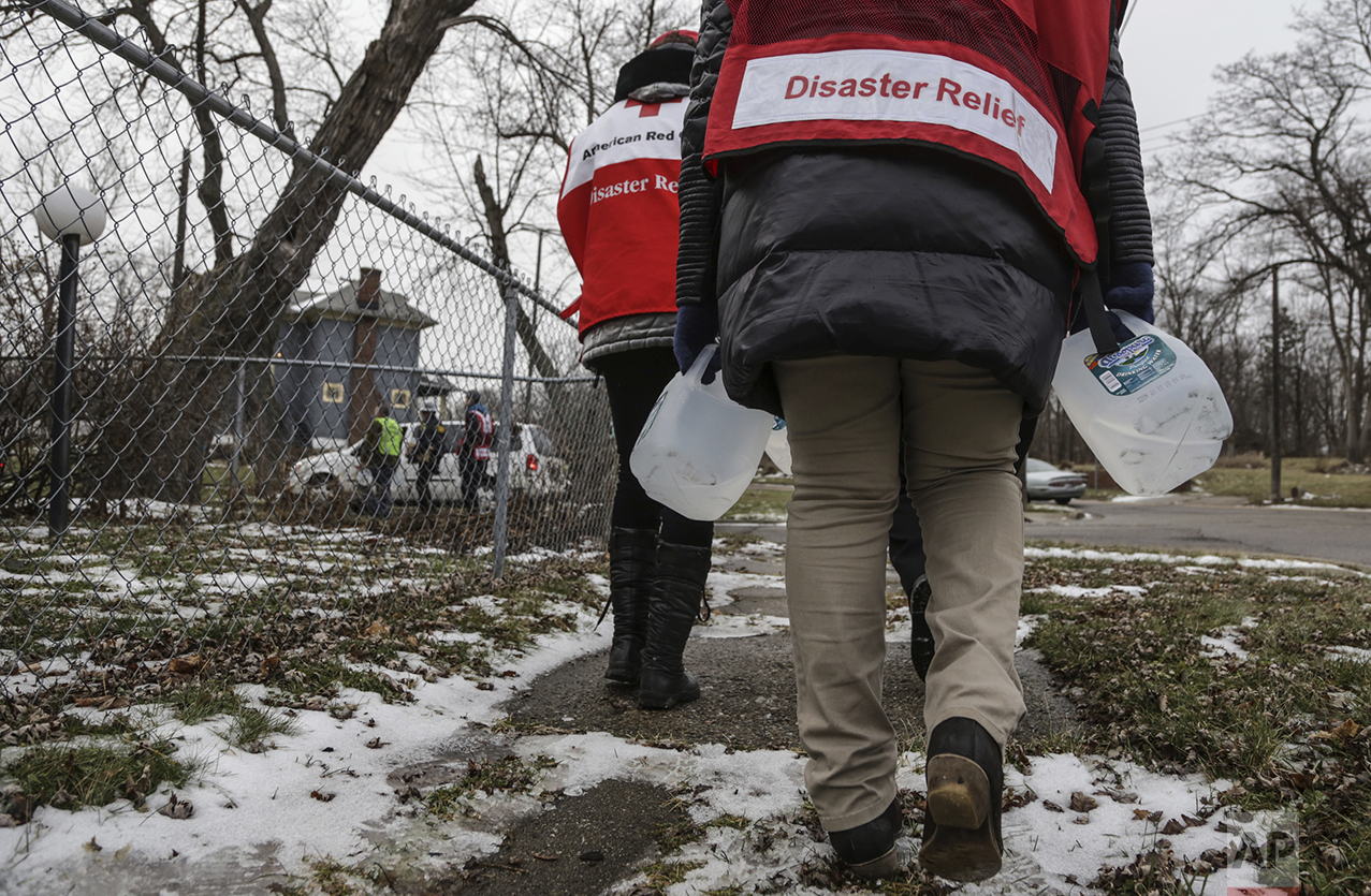  Members of the Red Cross deliver jugs of free purified water and water filters door-to-door to residents dealing with the water crisis on the north side of Flint, Mich., on Jan. 8, 2016. (Ryan Garza/Detroit Free Press via AP) 