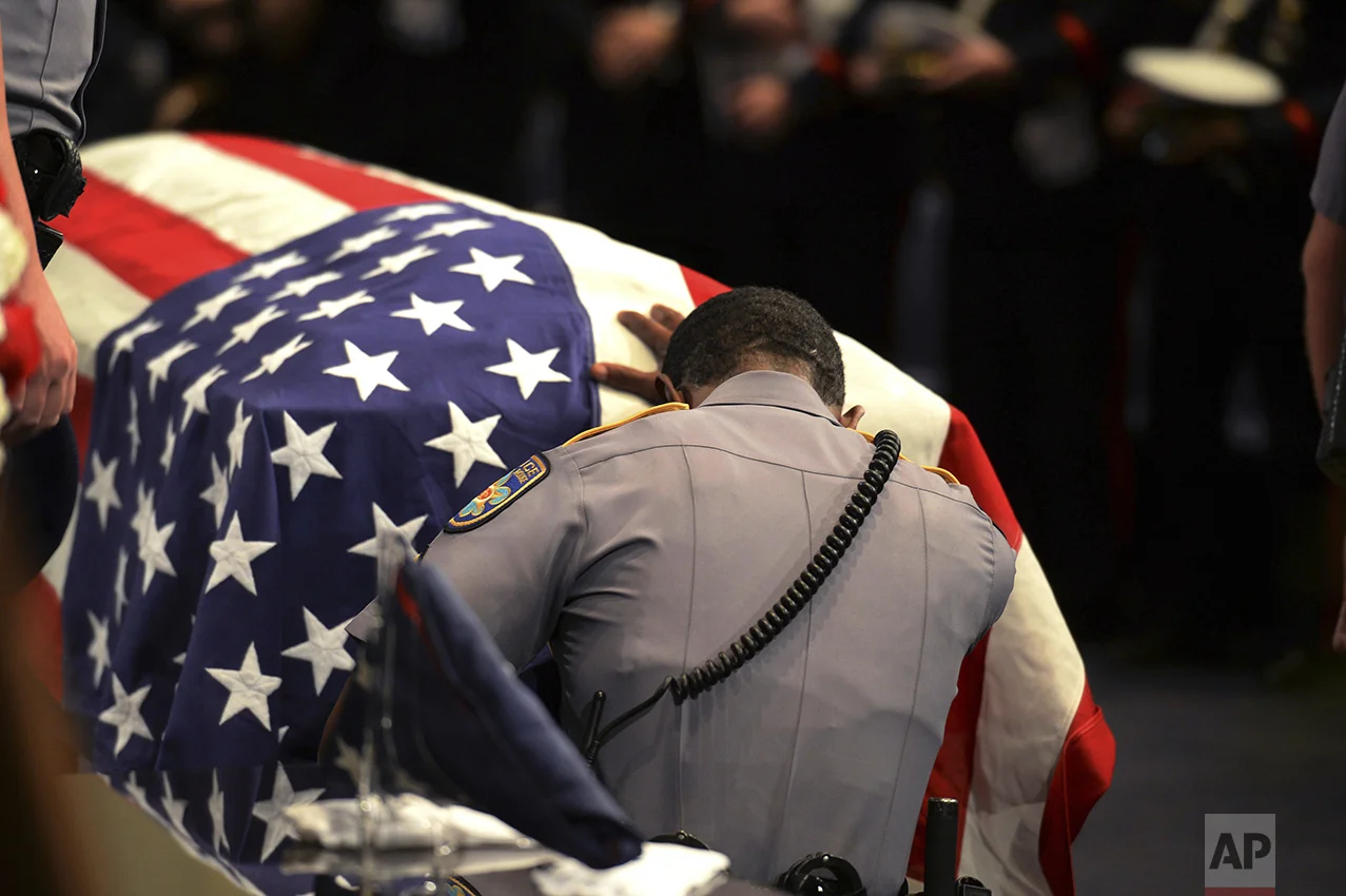 A member of Baton Rouge police Cpl. Montrell Jackson's unit kneels and touches his casket during his funeral service at the Living Faith Christian Center in Baton Rouge, La., on July 25, 2016. Jackson, slain by a gunman who authorities said targeted law enforcement, is the last of the three Louisiana law enforcement officers killed in an ambush to be buried. (Patrick Dennis/Baton Rouge Advocate via AP, Pool)