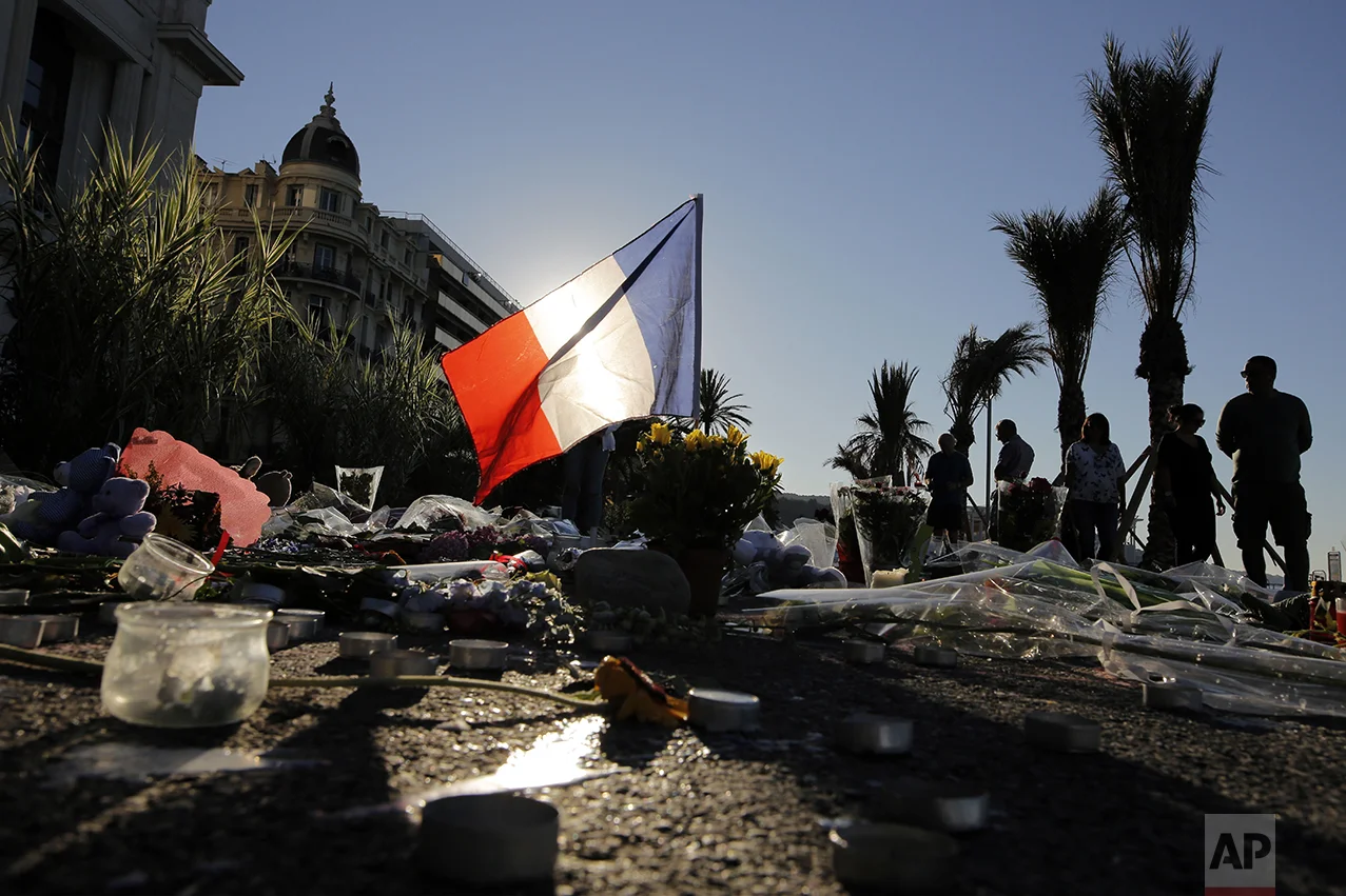 A French flag stands tall within a floral tribute for the victims killed during a deadly attack on the famed Boulevard des Anglais in Nice, southern France, on July 17, 2016. (AP Photo/Laurent Cipriani)