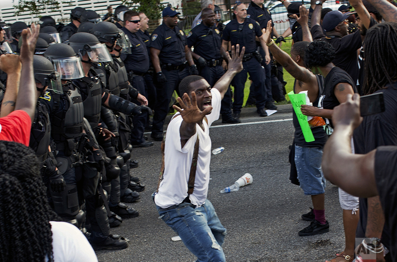  A man attempts to stop protesters from engaging with police in riot gear in front of the Police Department headquarters in Baton Rouge, La., after police attempted to clear the street on July 9, 2016. Several protesters were arrested. (AP Photo/Max 