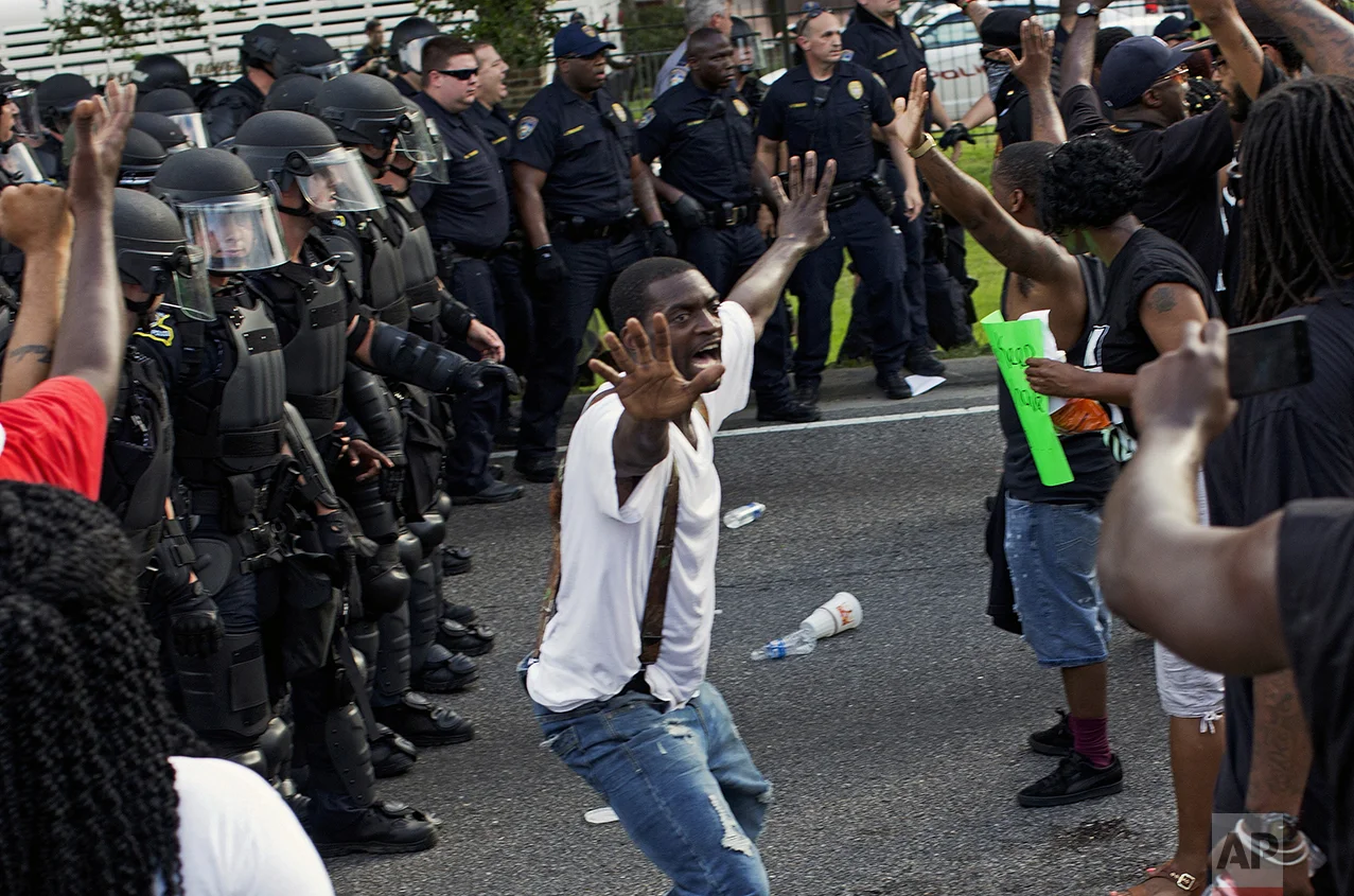 A man attempts to stop protesters from engaging with police in riot gear in front of the Police Department headquarters in Baton Rouge, La., after police attempted to clear the street on July 9, 2016. Several protesters were arrested. (AP Photo/Max Becherer)