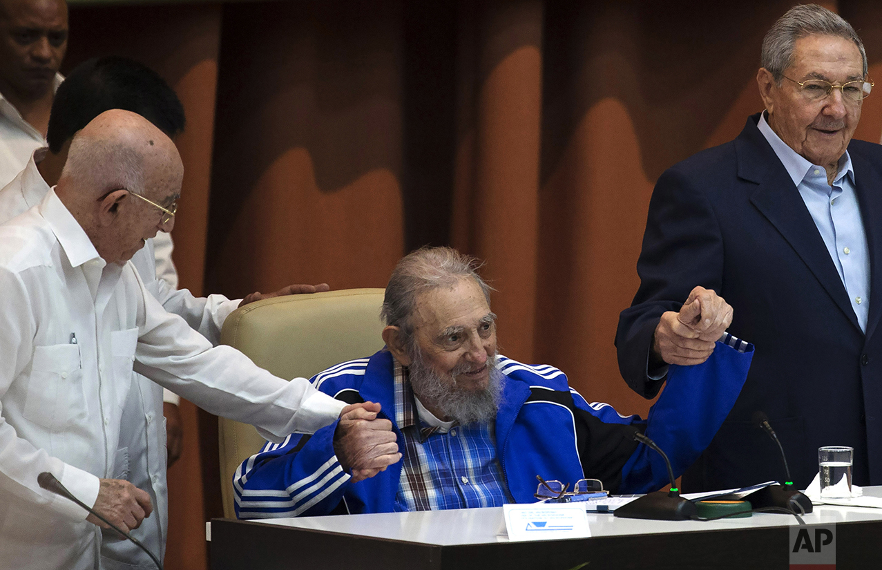  Fidel Castro sits as he clasps hands with his brother, Cuban President Raul Castro, right, and second secretary of the Central Committee, Jose Ramon Machado Ventura, moments before the playing of the Communist party hymn during the closing ceremonie
