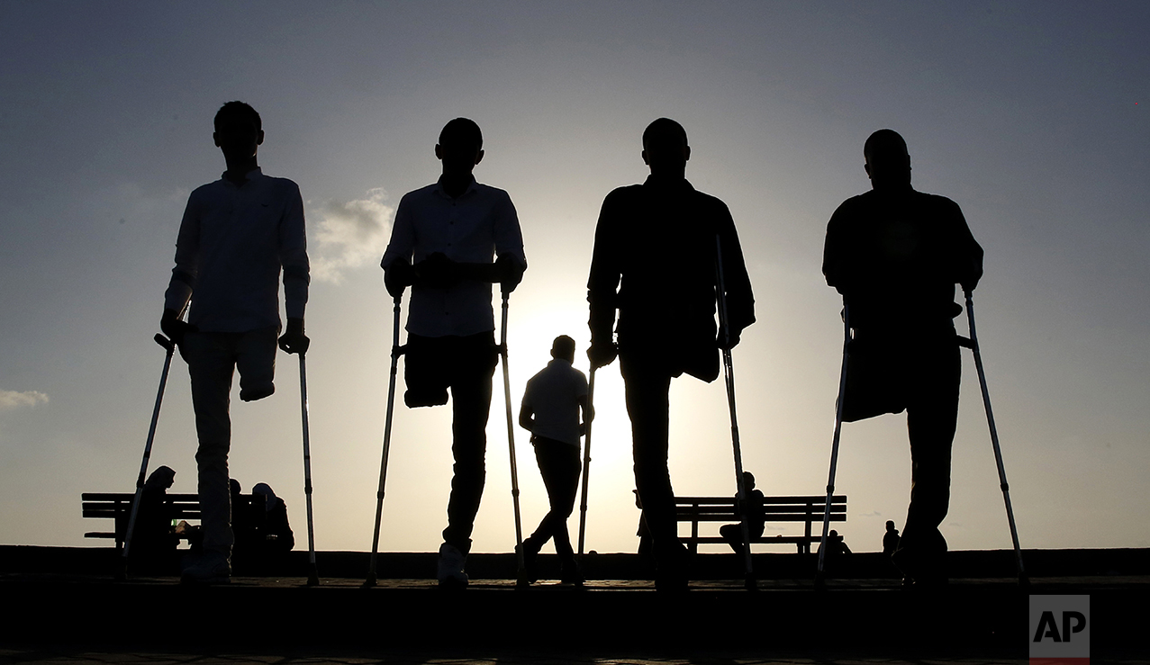 Four Palestinian friends who were injured during conflicts walk by the sea at Gaza's small fishing harbor on Oct. 24, 2016. Fighting has left thousands of people with disabilities or no limbs in this Palestinian enclave. (AP Photo/Hatem Moussa)