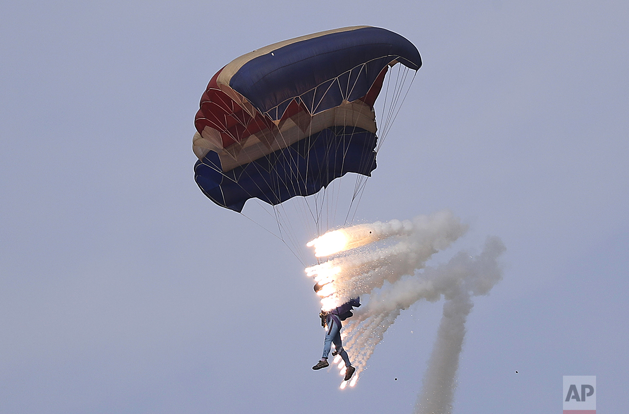 Pyrotechnics explode as a military parachutist descends upon Kalma Airport in Wonsan, North Korea, on Sept. 25, 2016. Thousands of Koreans and hundreds of foreign tourists and journalists invited to Wonsan, a port city, for the Wonsan International Friendship Air Festival, were given a glimpse of North Korea's own Air Force fighters, remote-controlled scale mock-up planes including an F-16 fighter jet, and demonstrations of military parachuting, with the first two skydivers descending with huge North Korean and ruling party flags. (AP Photo/Wong Maye-E)