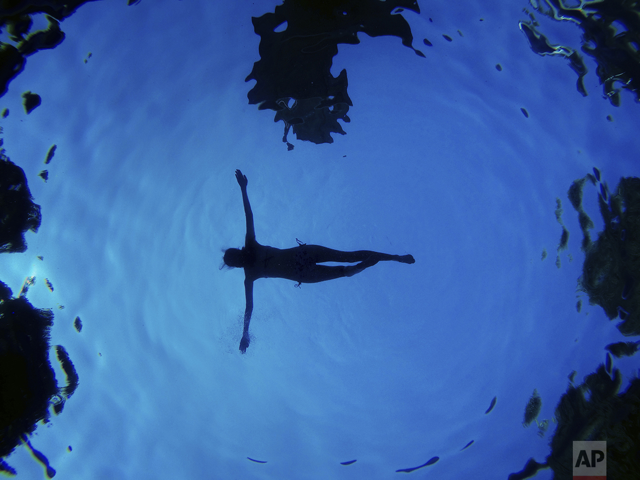 In this underwater picture a woman floats in a swimming pool during a summer day in Madrid, Spain, Aug. 28, 2016. (AP Photo/Daniel Ochoa de Olza)