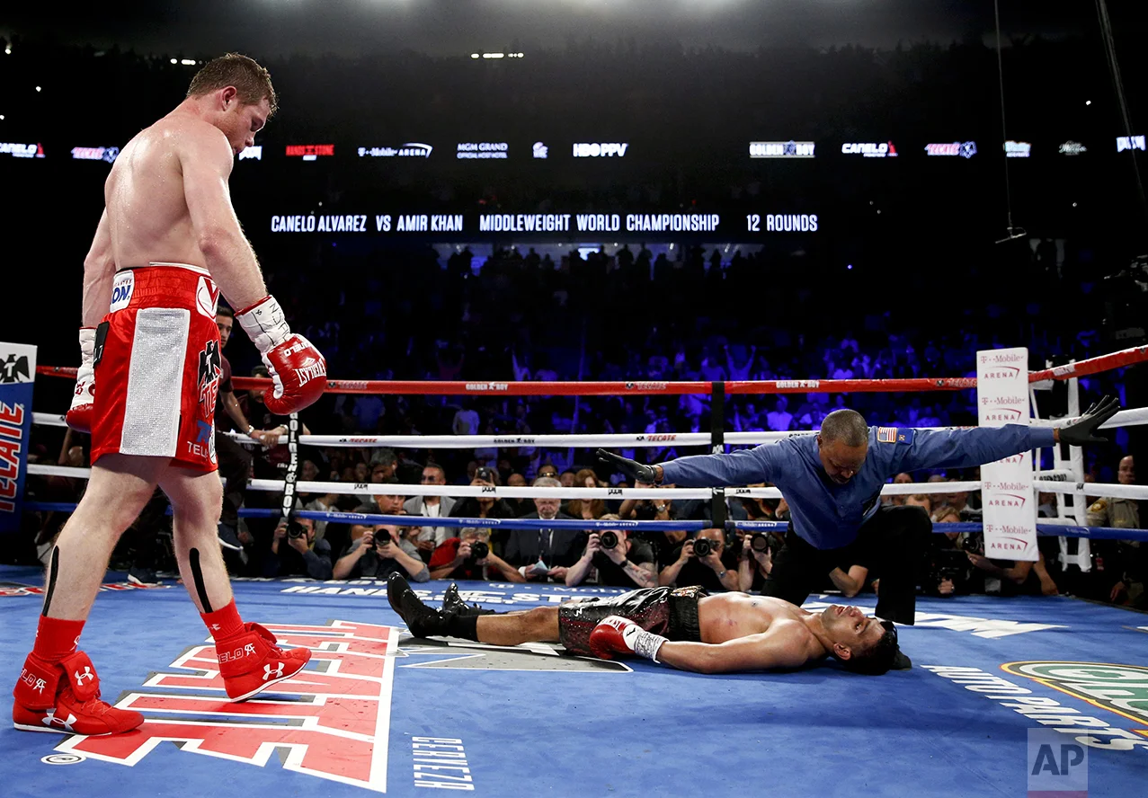 Canelo Alvarez, left, watches after knocking down Amir Khan during their WBC middleweight title fight on May 7, 2016, in Las Vegas. (AP Photo/John Locher)