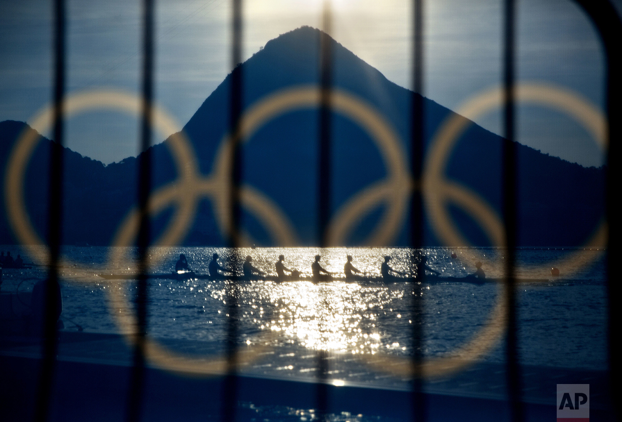  Rowers are seen through a screen decorated with the Olympic rings as they practice at the rowing venue in Lagoa at the 2016 Summer Olympics in Rio de Janeiro, Brazil, on Aug. 7, 2016. (AP Photo/David Goldman) 