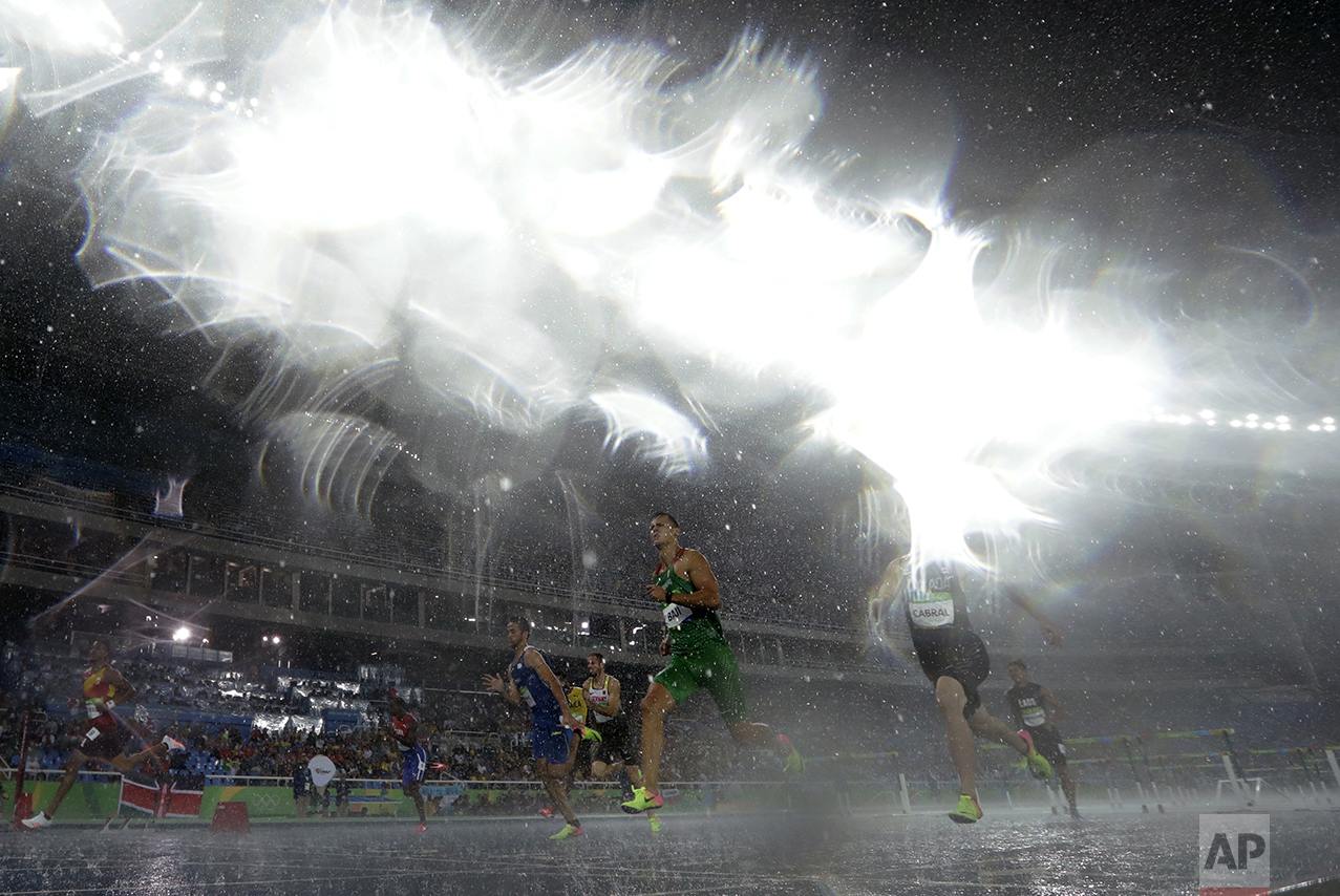  Hungary's Balazs Baji, center, and Canada's Johnathan Cabral compete in a men's 110-meter hurdles heat during heavy rain at the athletics competitions of the 2016 Summer Olympics at the Olympic stadium in Rio de Janeiro, Brazil, on Aug. 15, 2016. (A