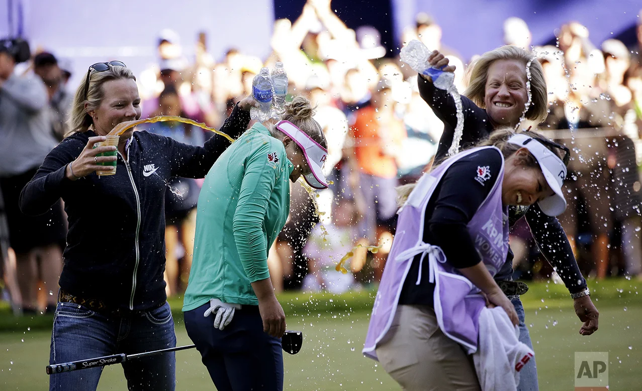Brooke Henderson, of Canada, second left, and her caddy and sister Brittany Henderson are doused with water and sports drinks on the 18th green after Brooke Henderson won the Women's PGA Championship golf tournament at Sahalee Country Club on June 12, 2016, in Sammamish, Wash. (AP Photo/Elaine Thompson)
